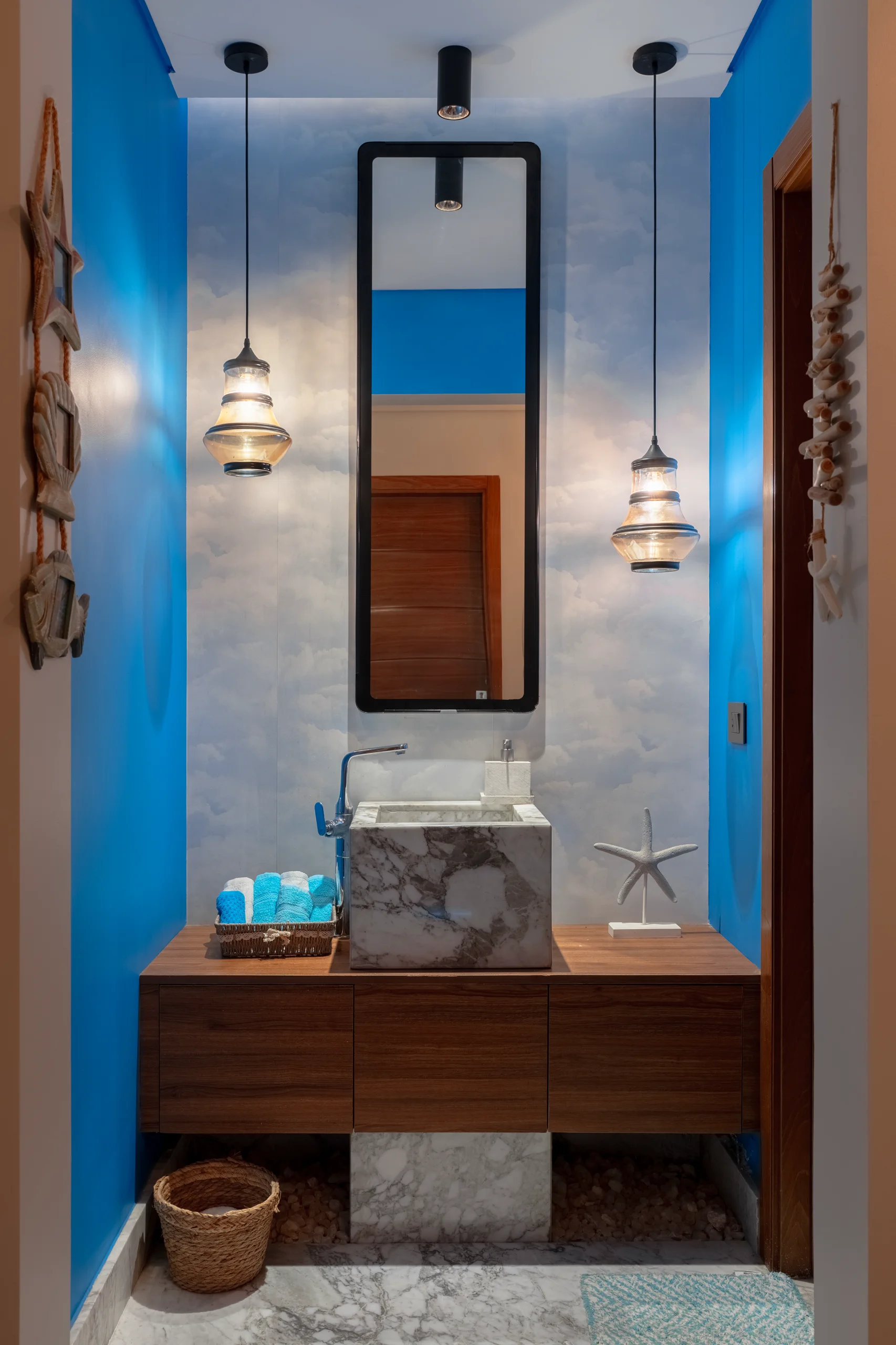 Blue powder-room vanity at Caesar SODIC Villa with walnut joinery and decorative pendant lighting.