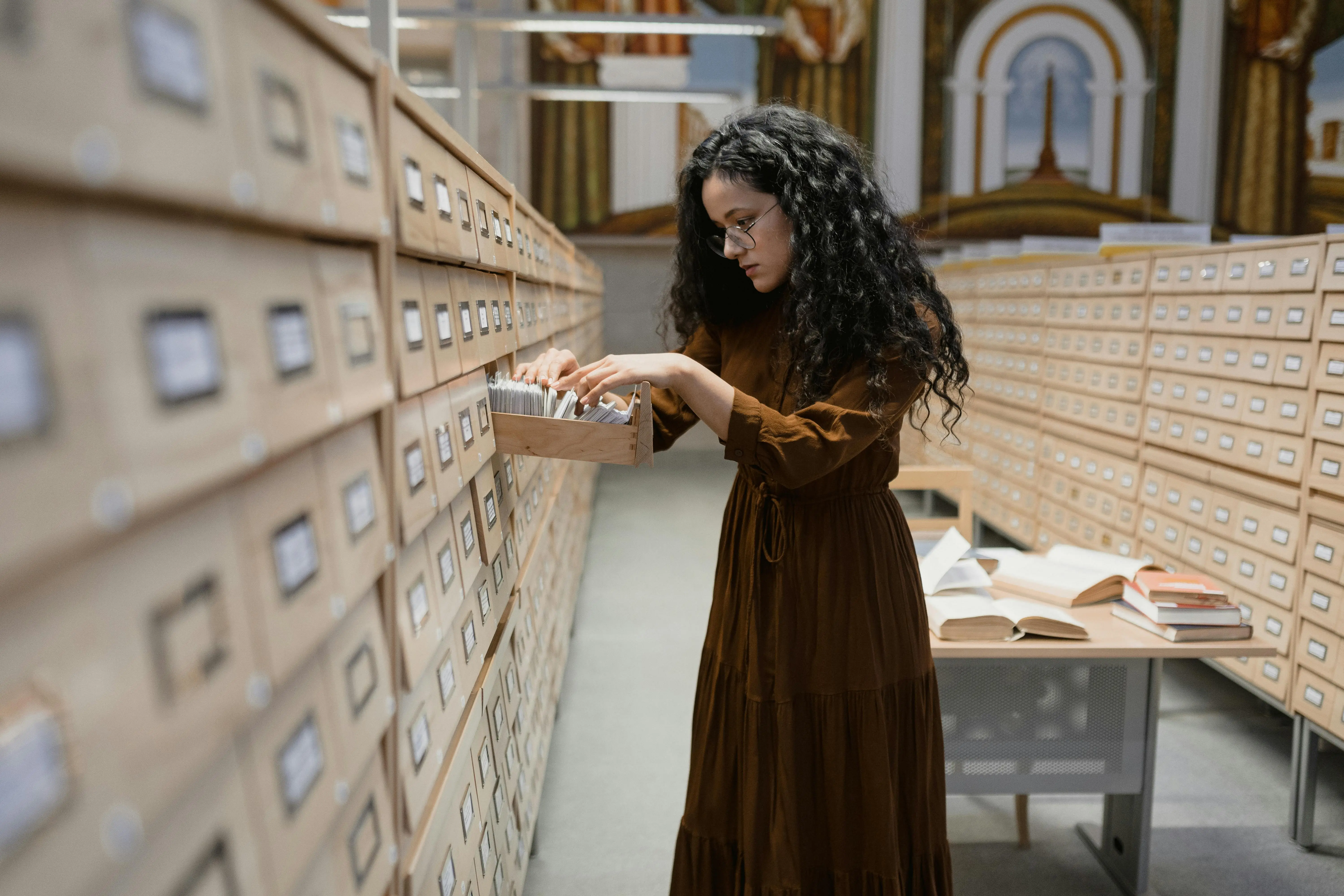 Historian examining file-filled lockers, searching through folders and documents, representing the careful process of uncovering and preserving local history.