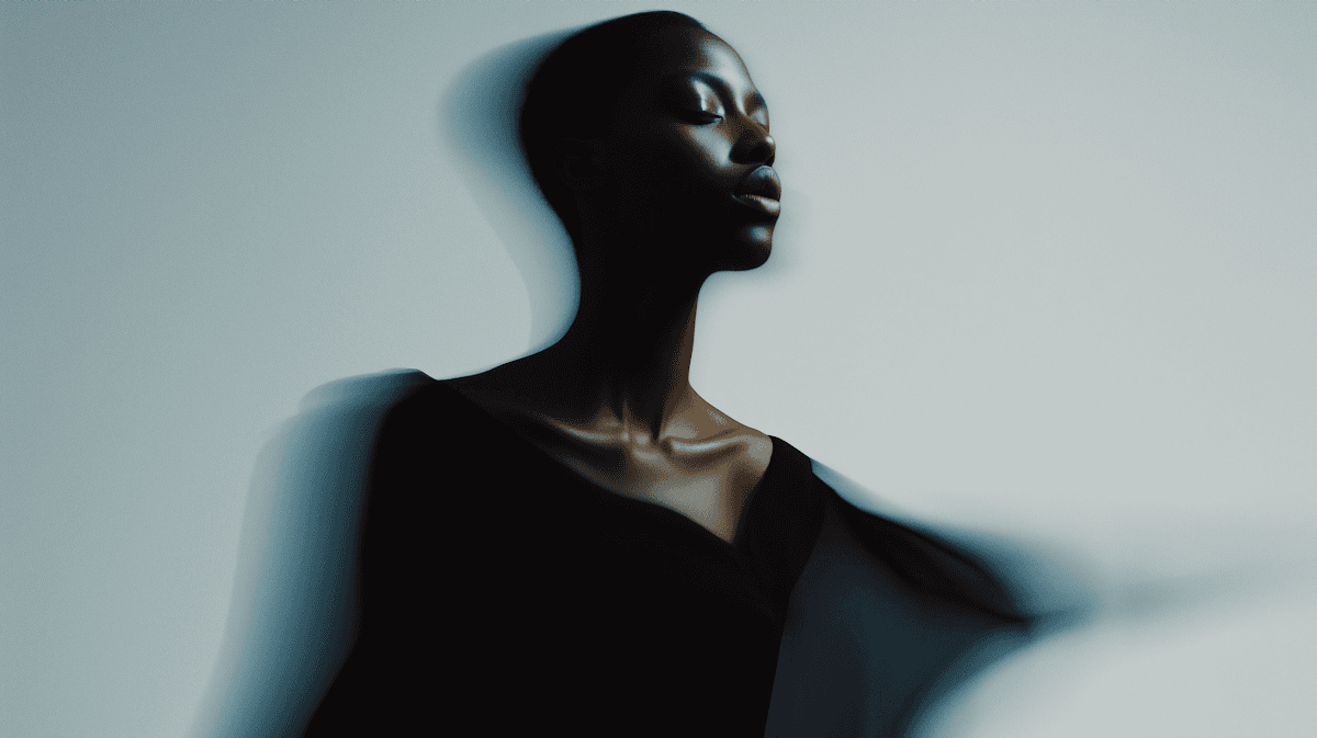 Silhouette of a person in a dark outfit, with dramatic lighting creating a striking profile against a soft background.