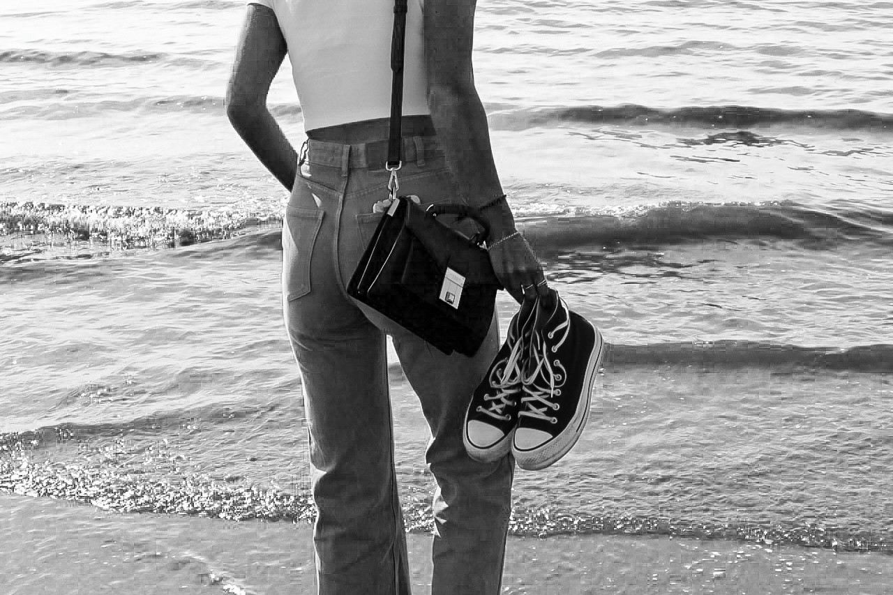 Lifestylefoto van een meisje met schoenen die op het strand wandelt, met de focus op de serene interactie tussen haar en de natuurlijke omgeving