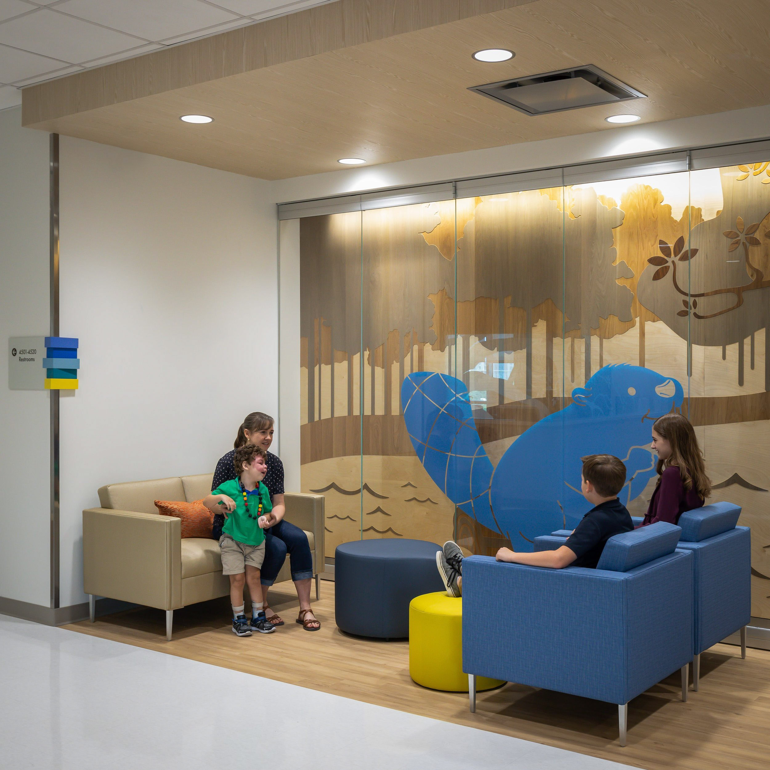 Family sitting in a waiting room with woodland mural.