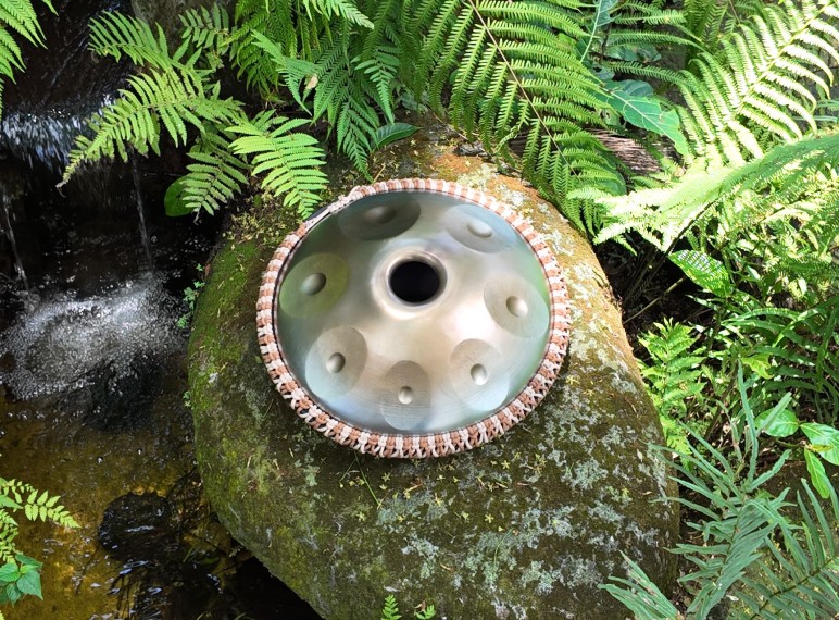 Top view of a stainless steel handpan on a rock.