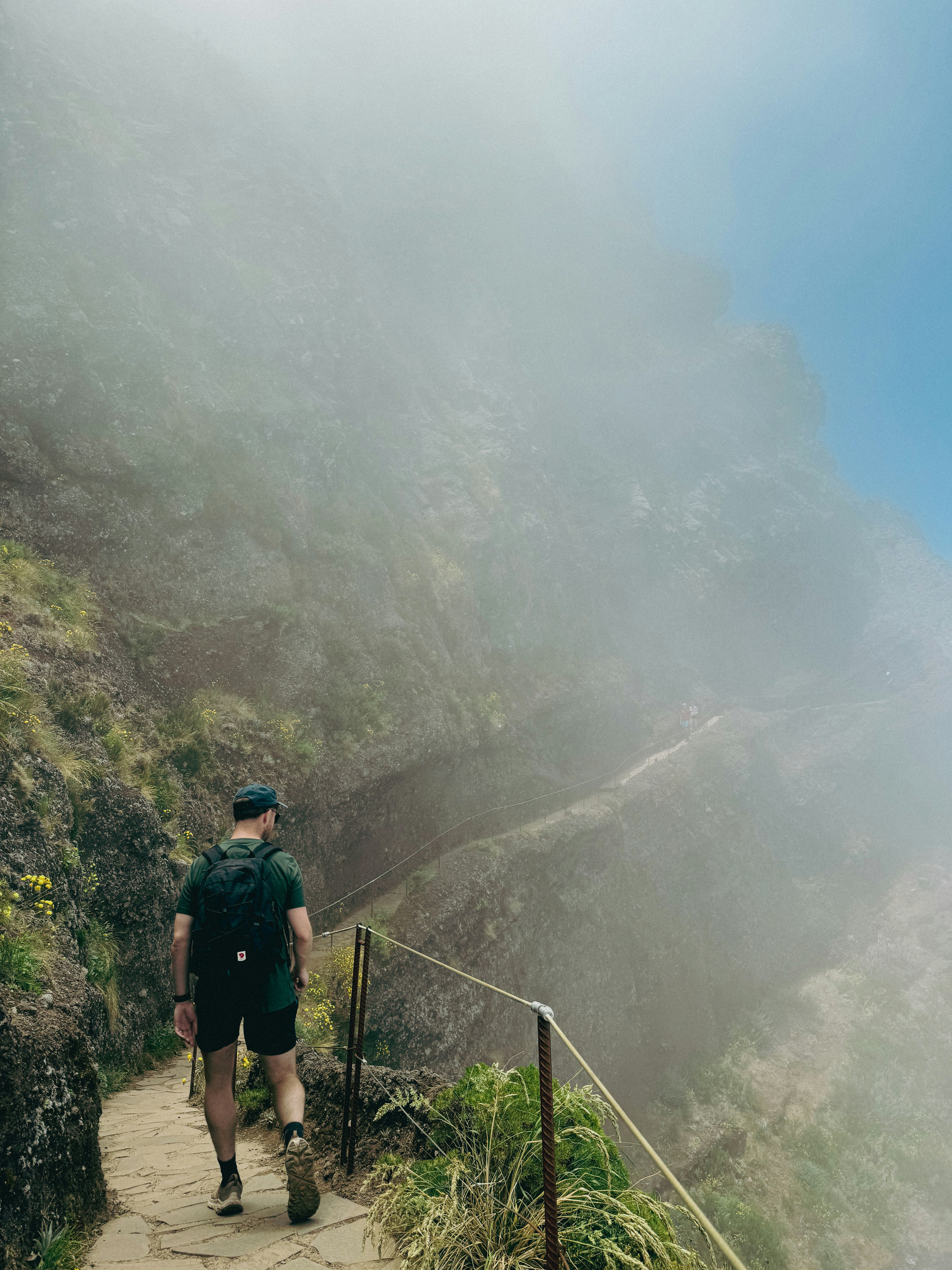 A man climbing a mountain path on a misty day