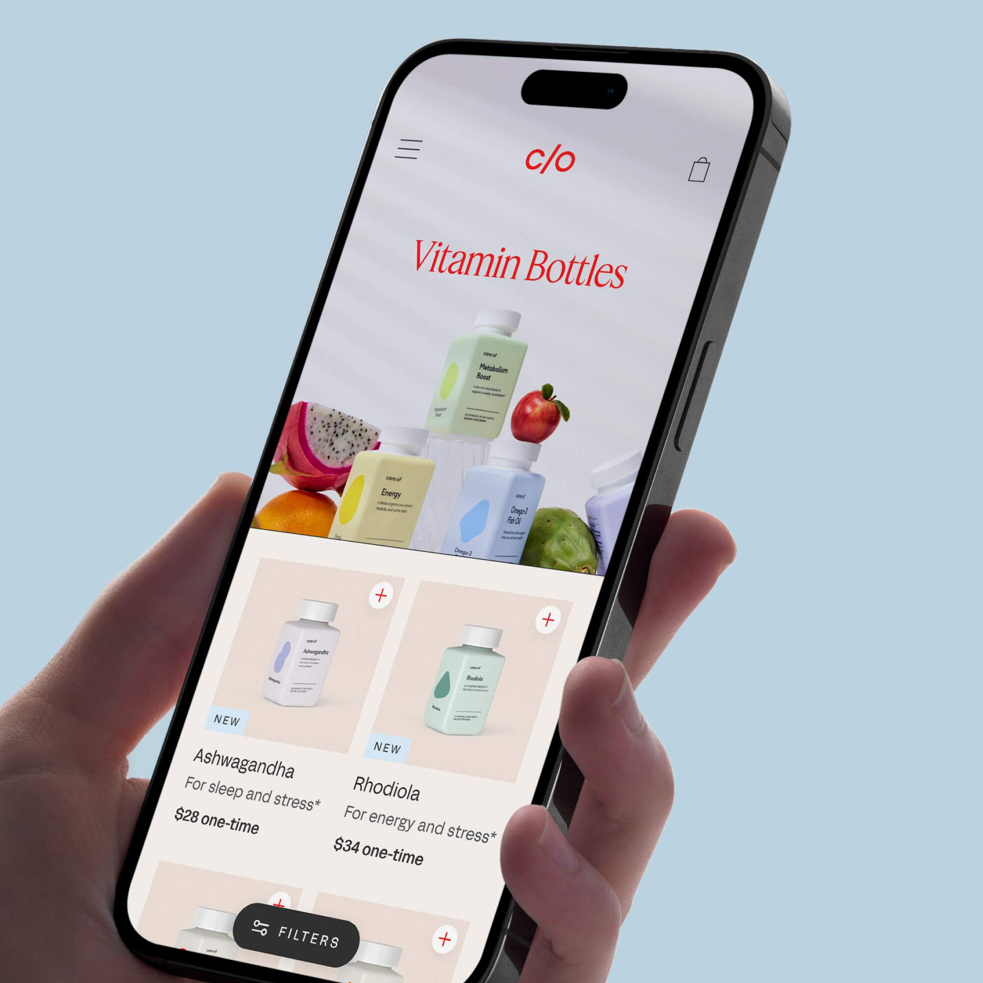 Hand holding a smartphone showing the Care/of interface with various vitamin bottles and supplement options.