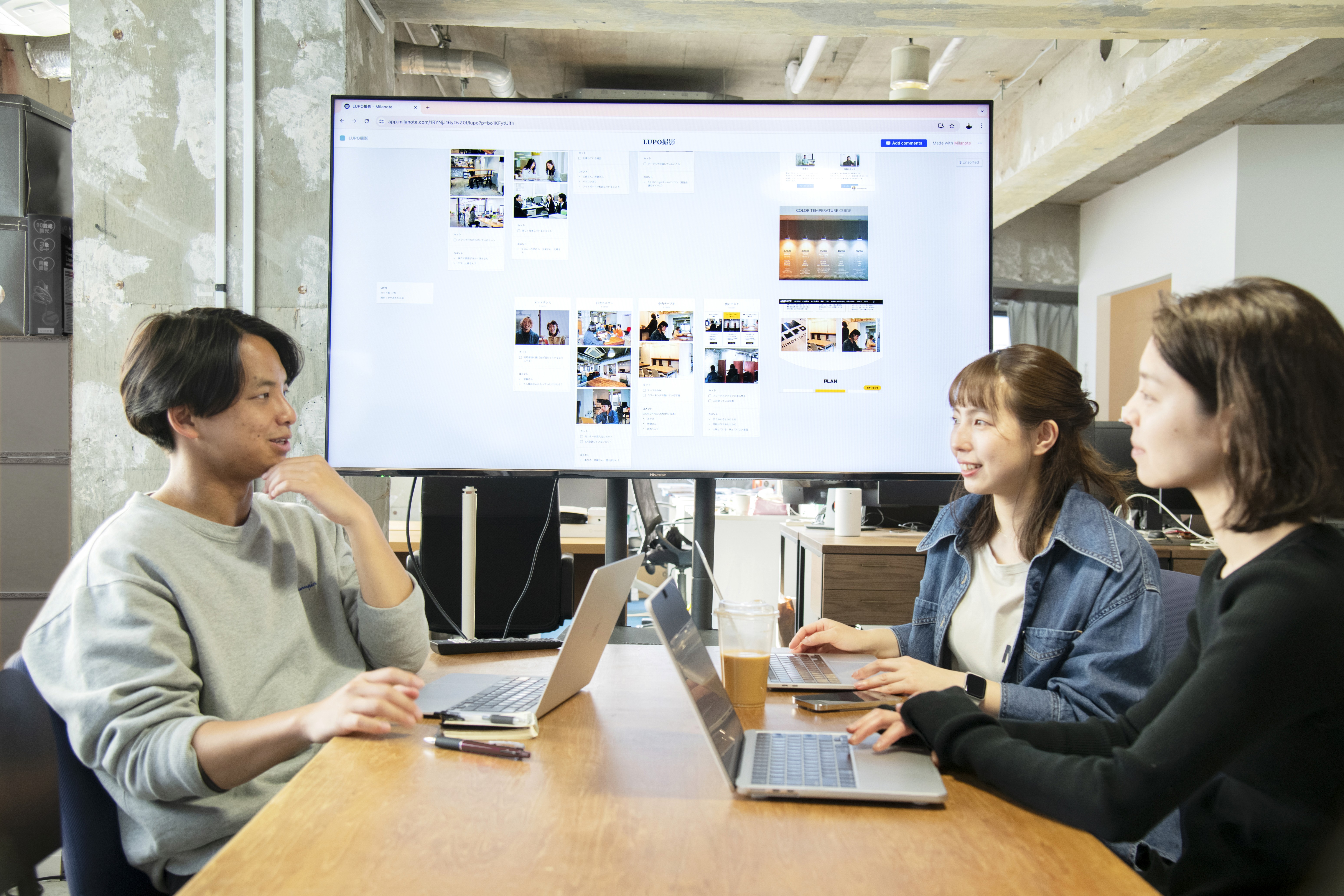 Business team collaborating in meeting room with whiteboard and notes on wall and table.