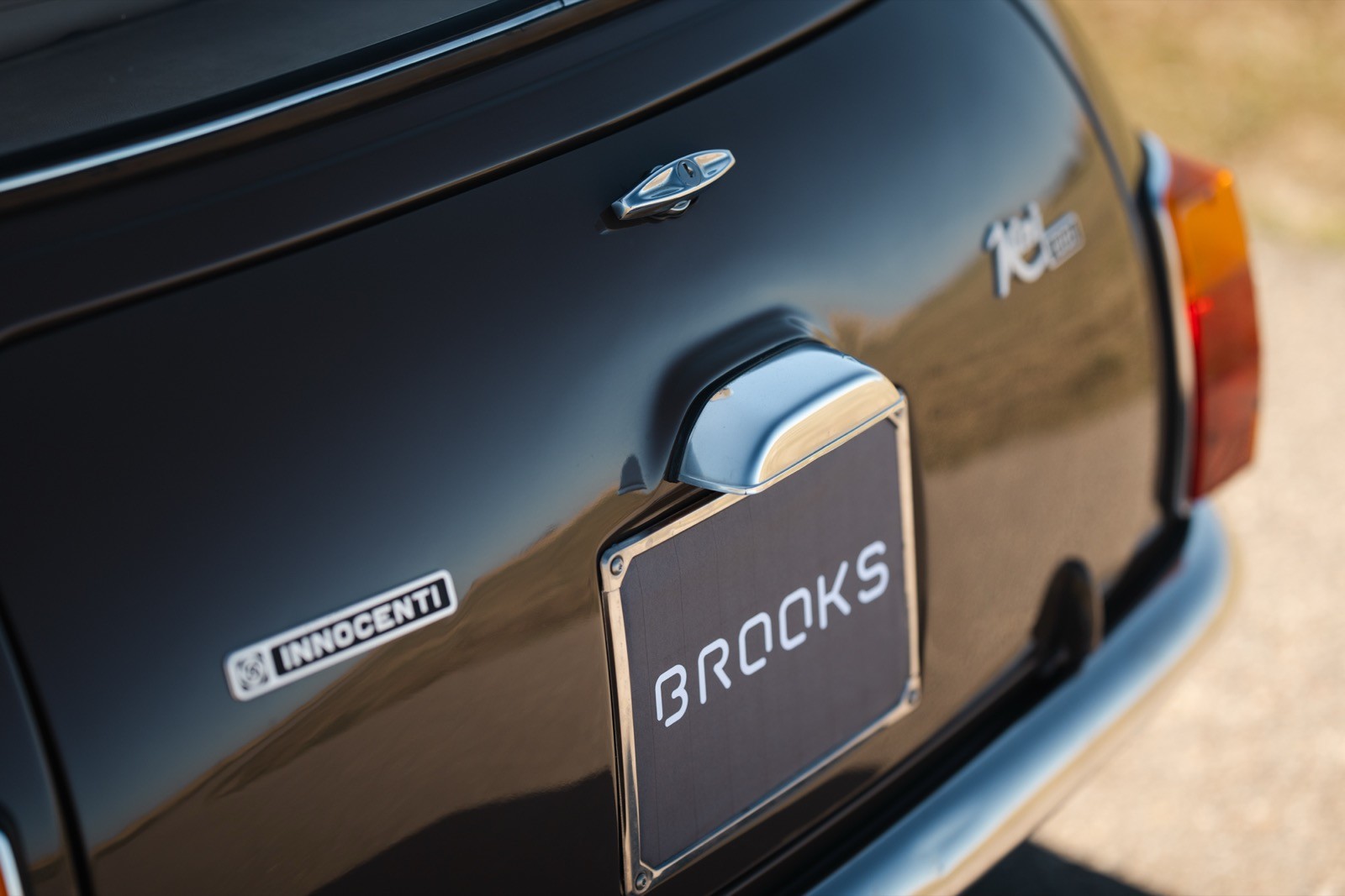 Close-up of the rear of a classic black car, featuring a round fuel cap and a simple license plate holder.