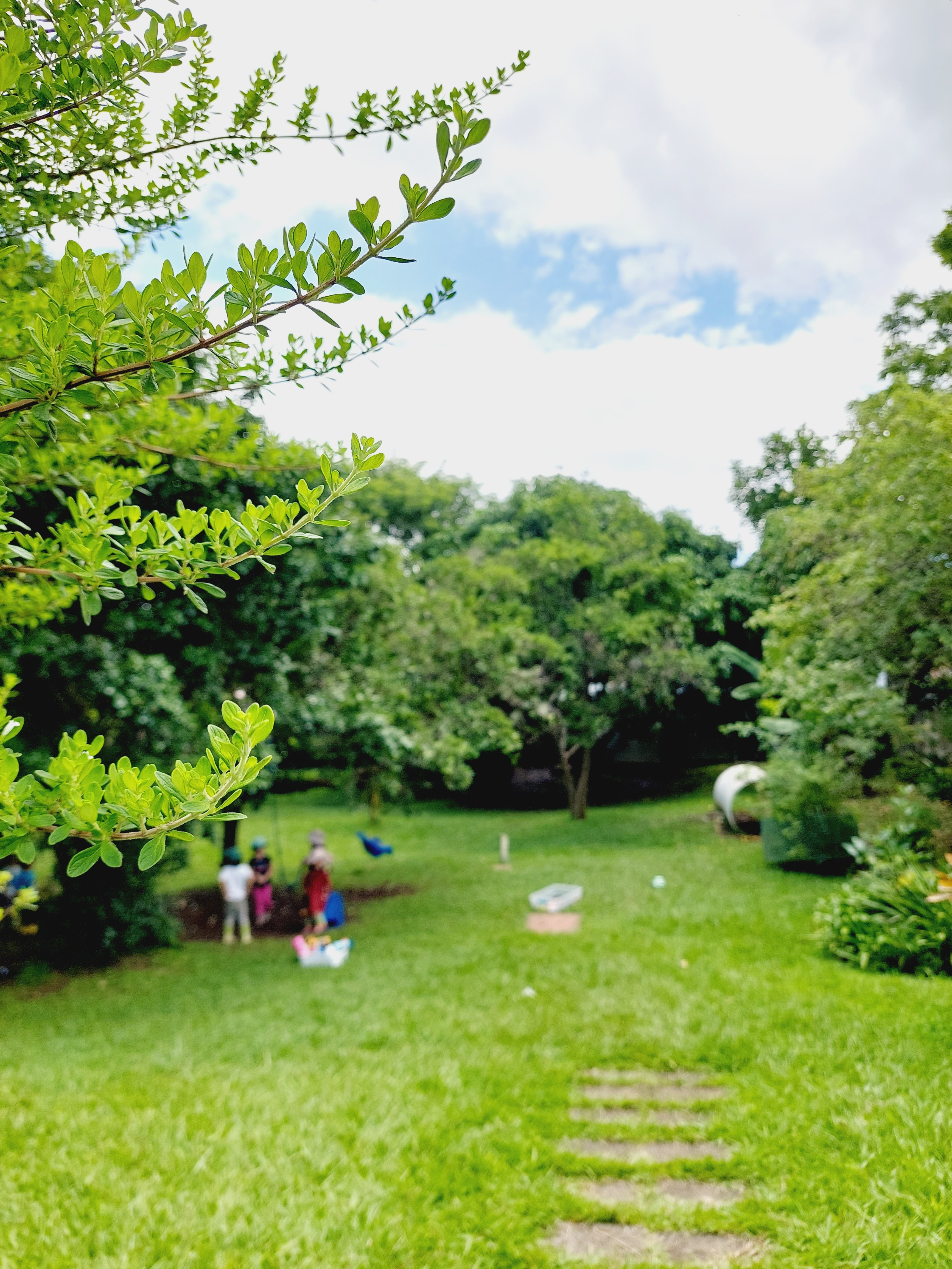 Amplio jardín natural con niños jugando, reflejando el espacio de juego al aire libre y la conexión con la naturaleza