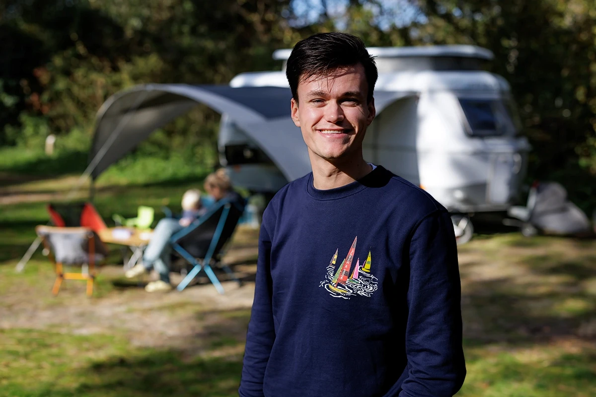 Medewerker van De Kennemer Duincampings op de camping met een caravan achter zich