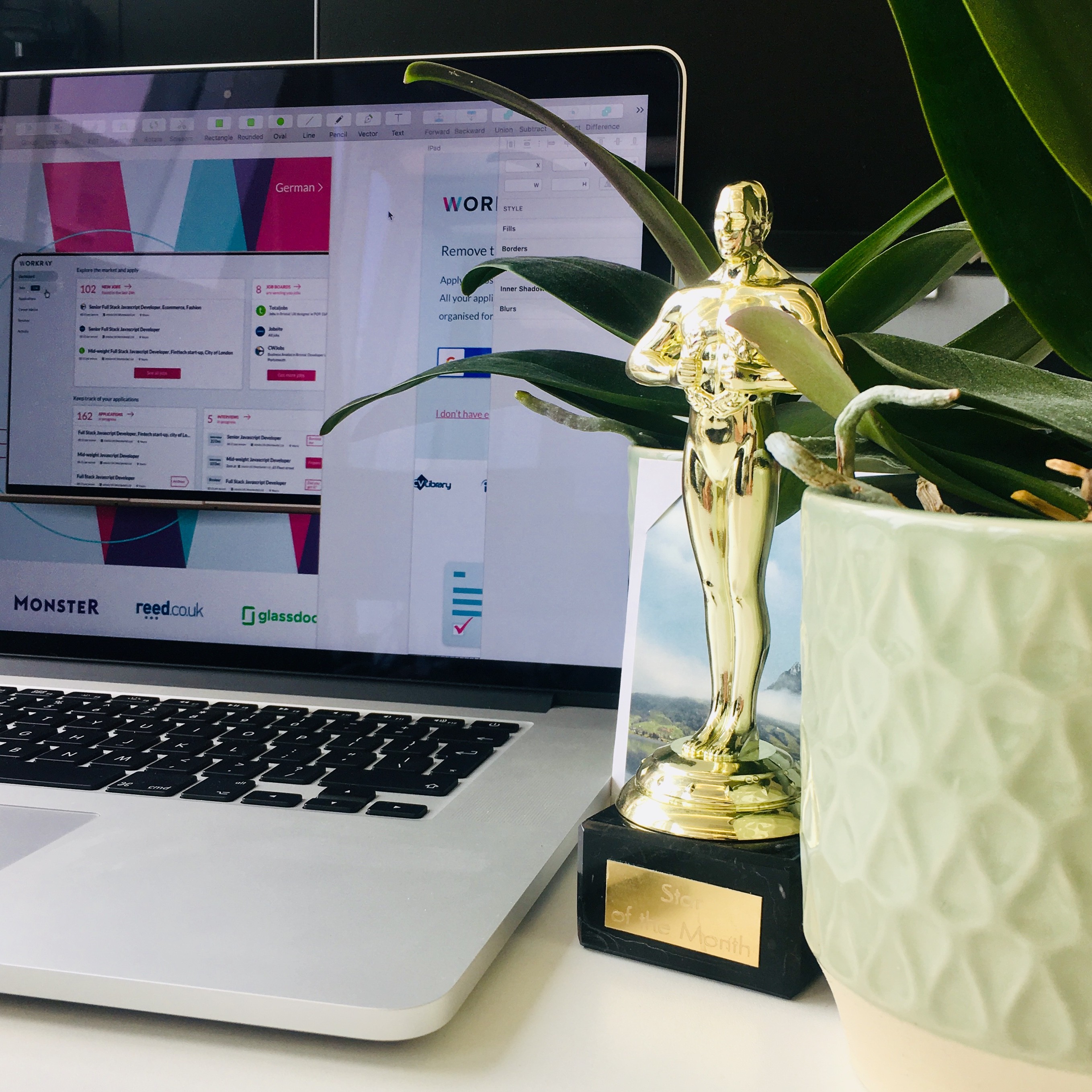 Trophey next to a orchid plant and laptop in the background with Workray on screen