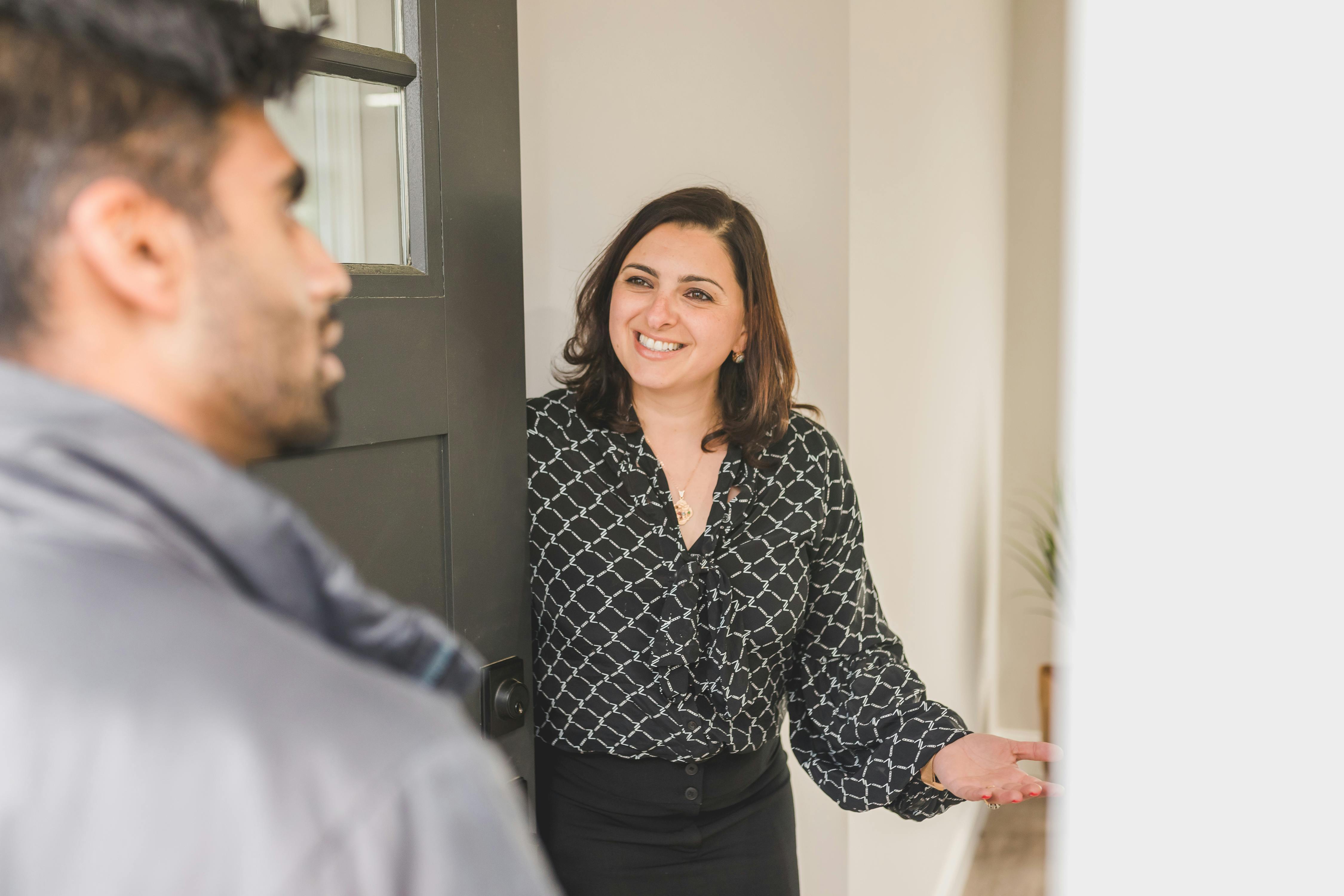 An estate agent welcoming a client into a house