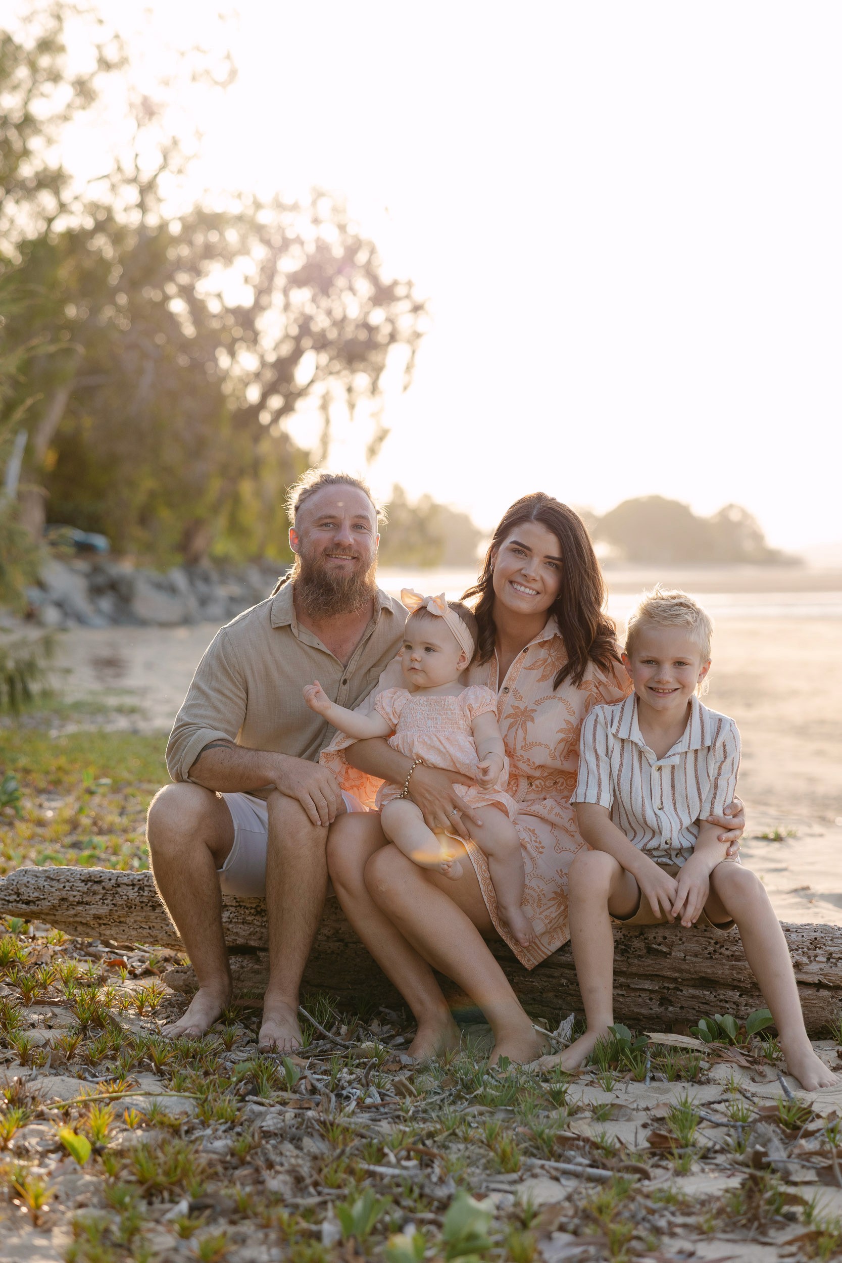 Family photographed sitting on a log at the beach in Mackay QLD