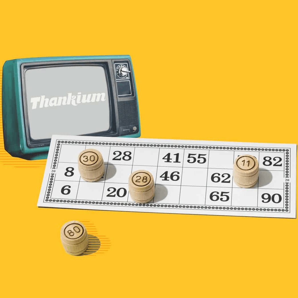 Juego de bingo con ficha sobre cartón y televisor retro de fondo.