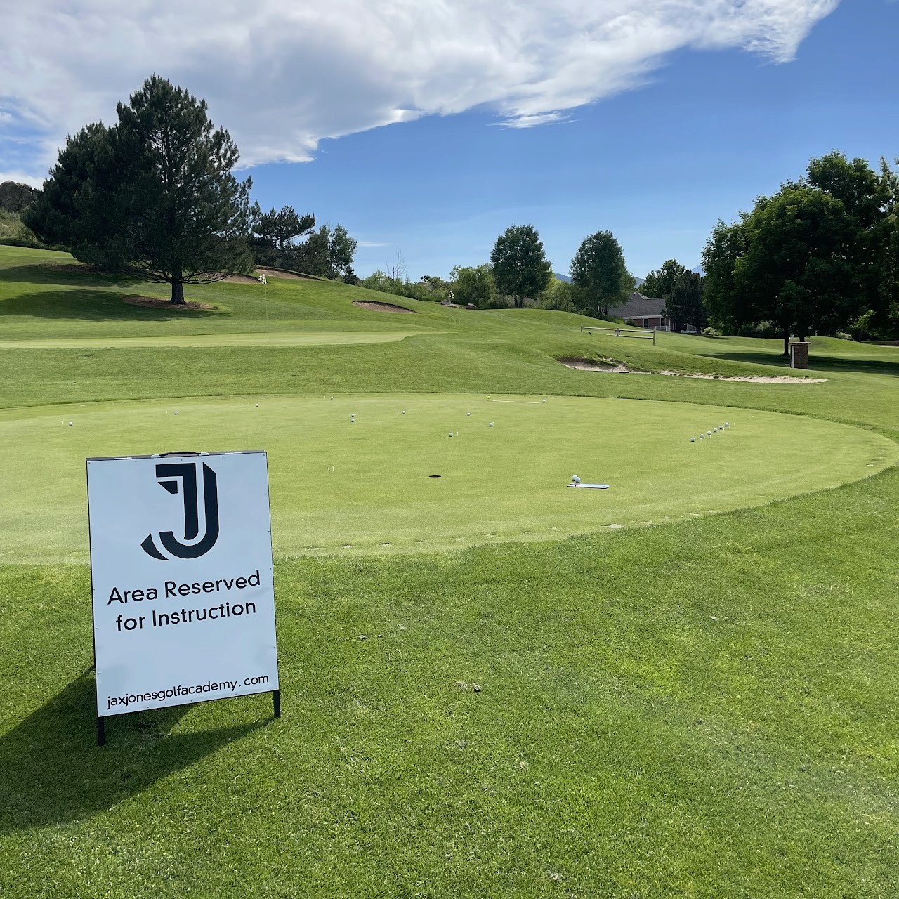 A golf course green with a sign posted with the JJGA logo reserving the area for instruction.