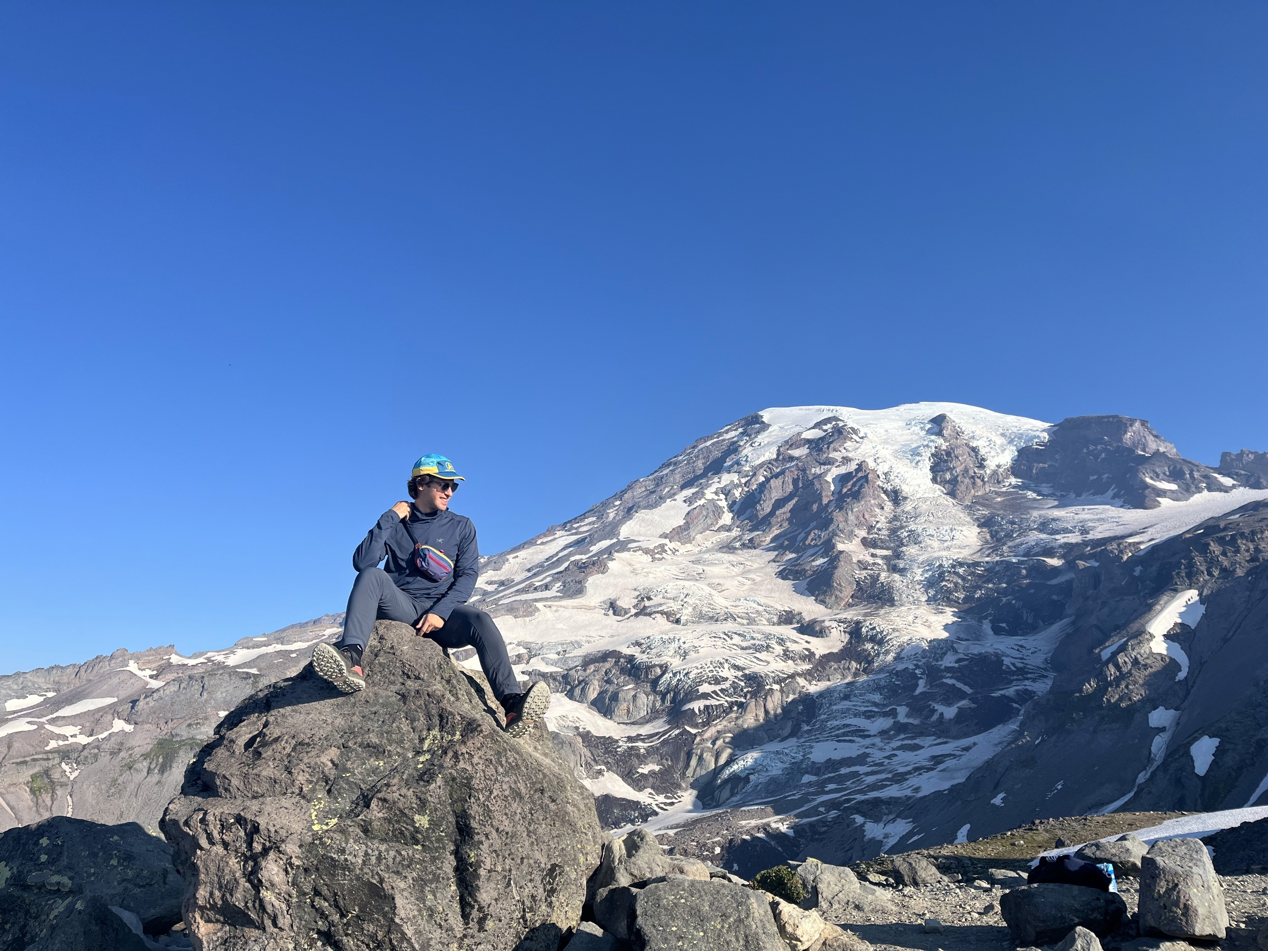 An image of me sitting on a rock with Mount Rainier in the background.