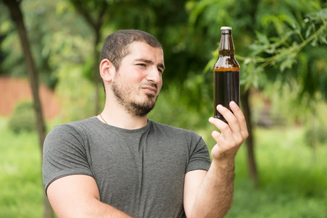 Person holding an alcohol bottle, symbolizing challenges of drinking habits and the journey to sobriety.