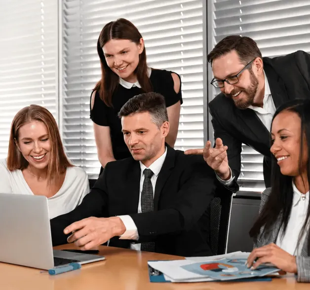 A group of people sitting around a table with laptops.