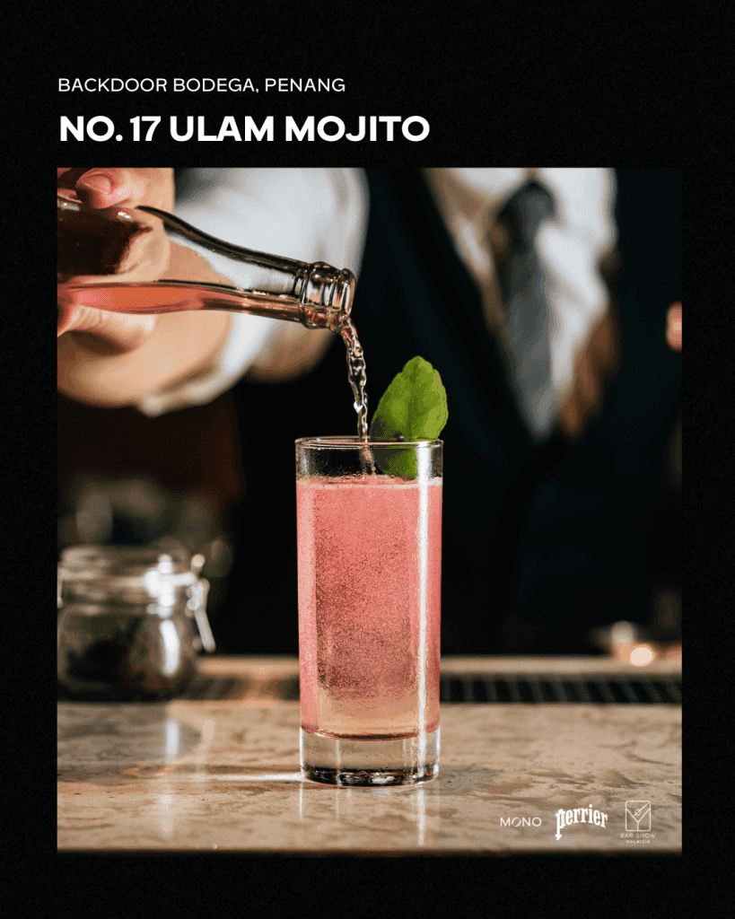A bartender pouring a sparkling drink into a tall glass, featuring a pink Ulam Mojito cocktail garnished with a fresh mint leaf, at Backdoor Bodega in Penang.