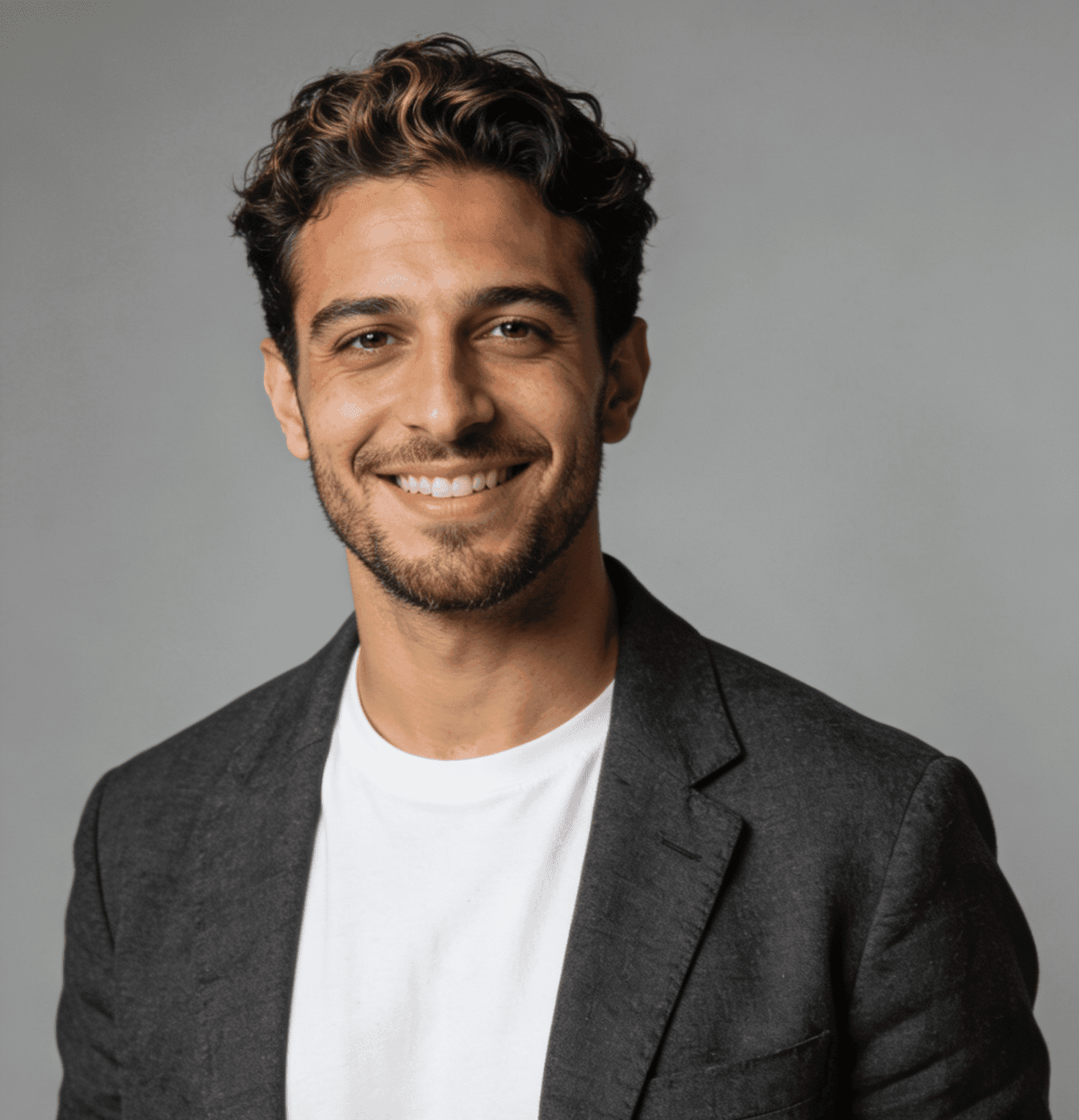 A man wearing a suit and white shirt, smiling cheerfully at the viewer.