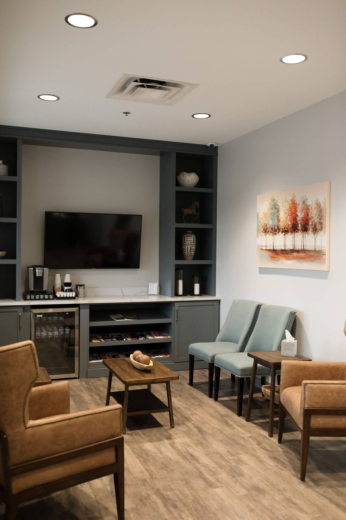 A cozy lounge area featuring two armchairs, a small table, a wall-mounted TV, and minimalist decor.