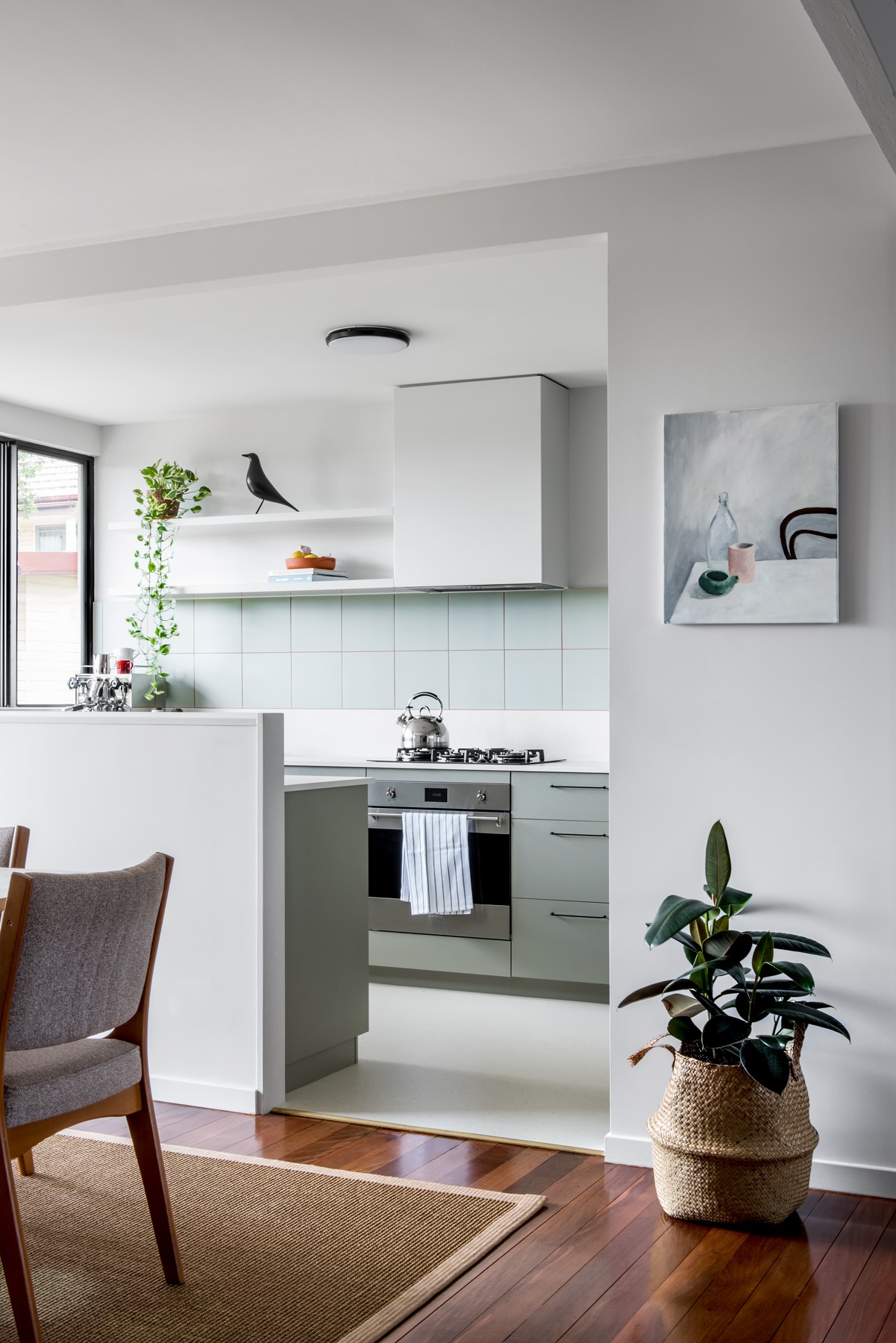 View from the dining area into Glenhaven Kitchen, showing the soft green joinery, integrated appliances, and a calm, light-filled connection between spaces.