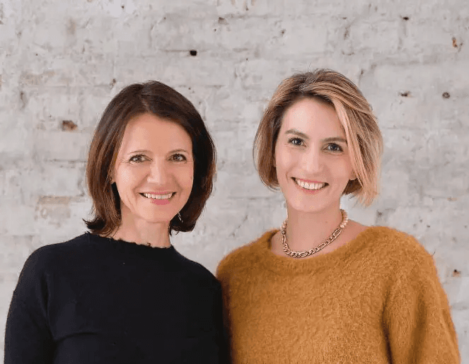 Frida Lüth und Ulrike Vollmoeller, Gründerinnen von IRIS&FRED, Portrait zweier Frauen vor einer hellen Backsteinwand.