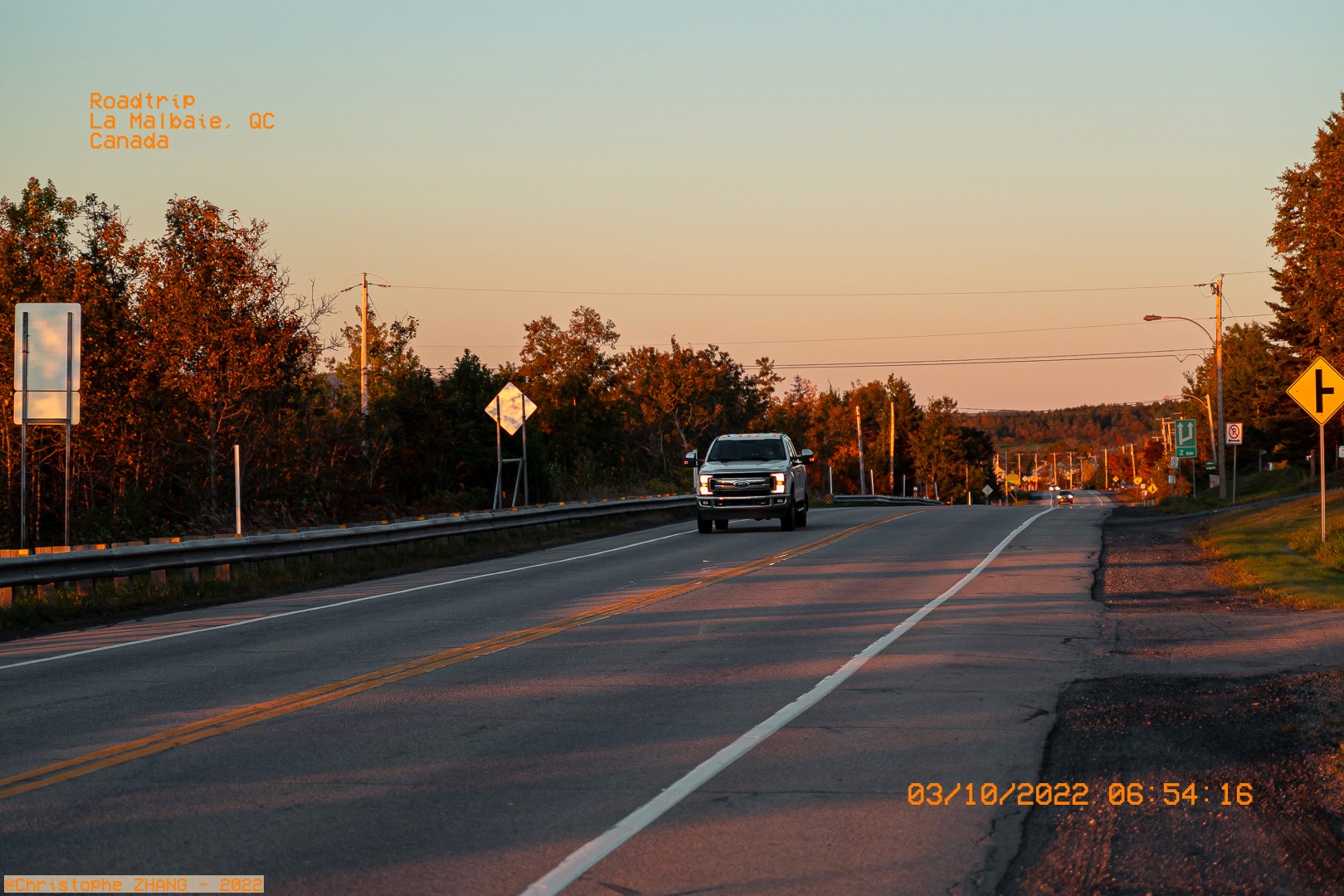 Lever du soleil sur une route tranquille à La Malbaie, avec des arbres aux couleurs d’automne