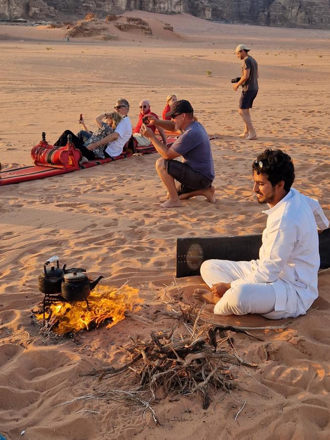 Guests and Bedouin guide watching the sunset in Wadi Rum, Jordan