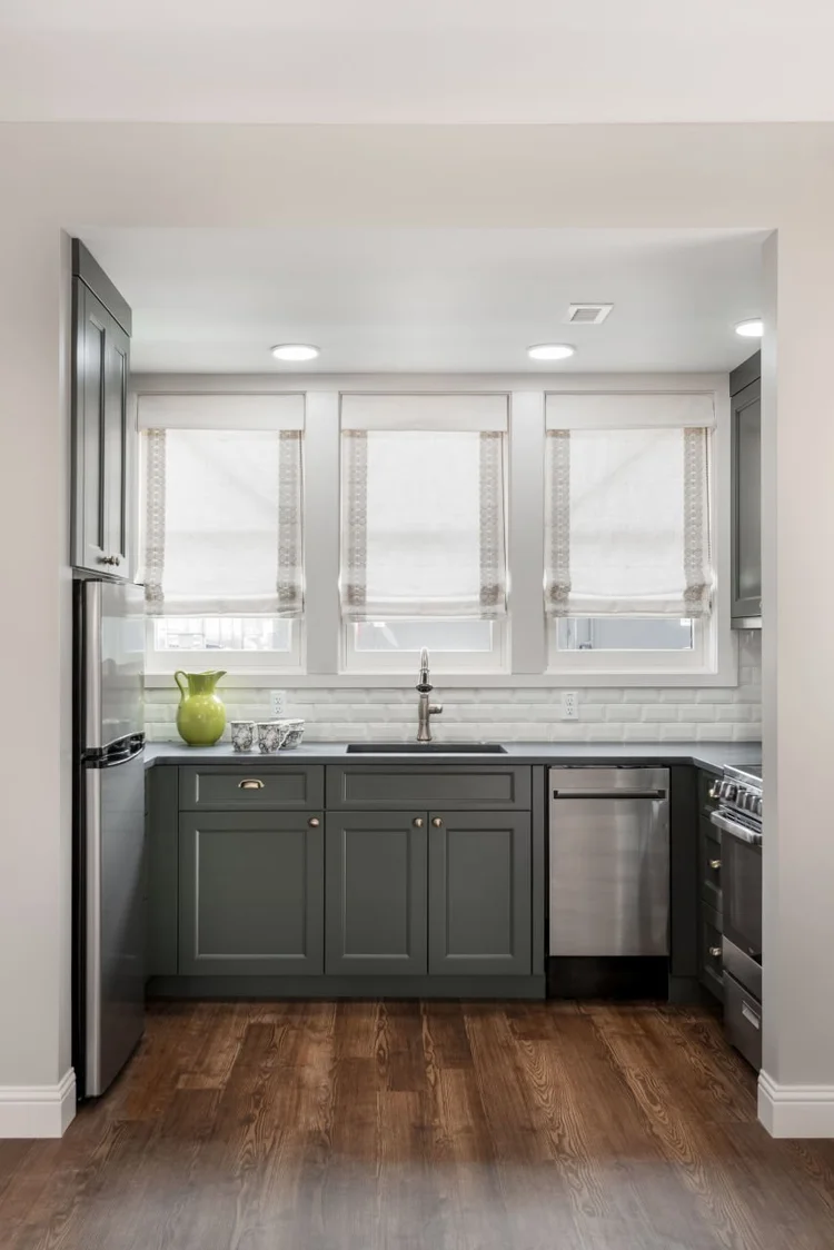 Kitchen with gray cabinets, stainless steel appliances and blinds.