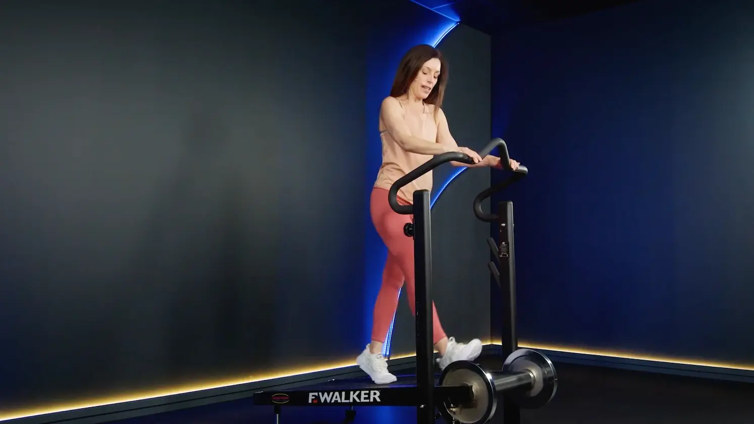 Femme en tenue de sport marchant sur un appareil de fitness dans un studio, réalisant un exercice doux