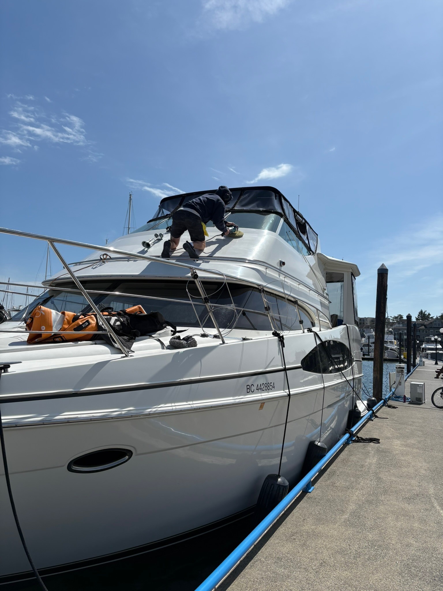 A man on a very large boat on the top of the boat cleaning and detailing the top of the boat at a marina