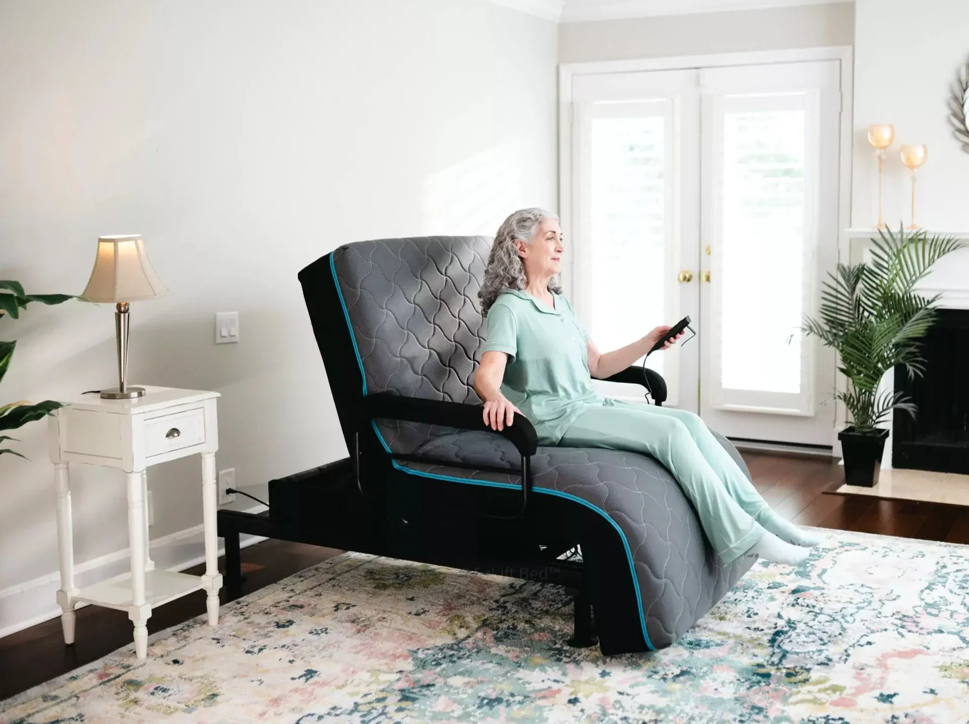 Alt text: An elderly woman is being supported from a sleeping to standing position by the adjustable bed.