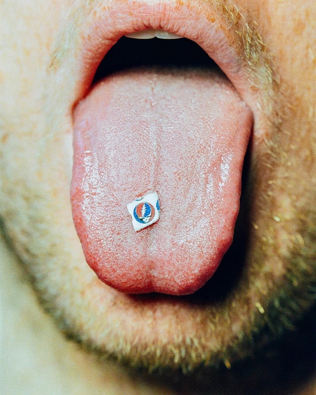 Close-up of a tongue with a small circular emblem resting on its surface.