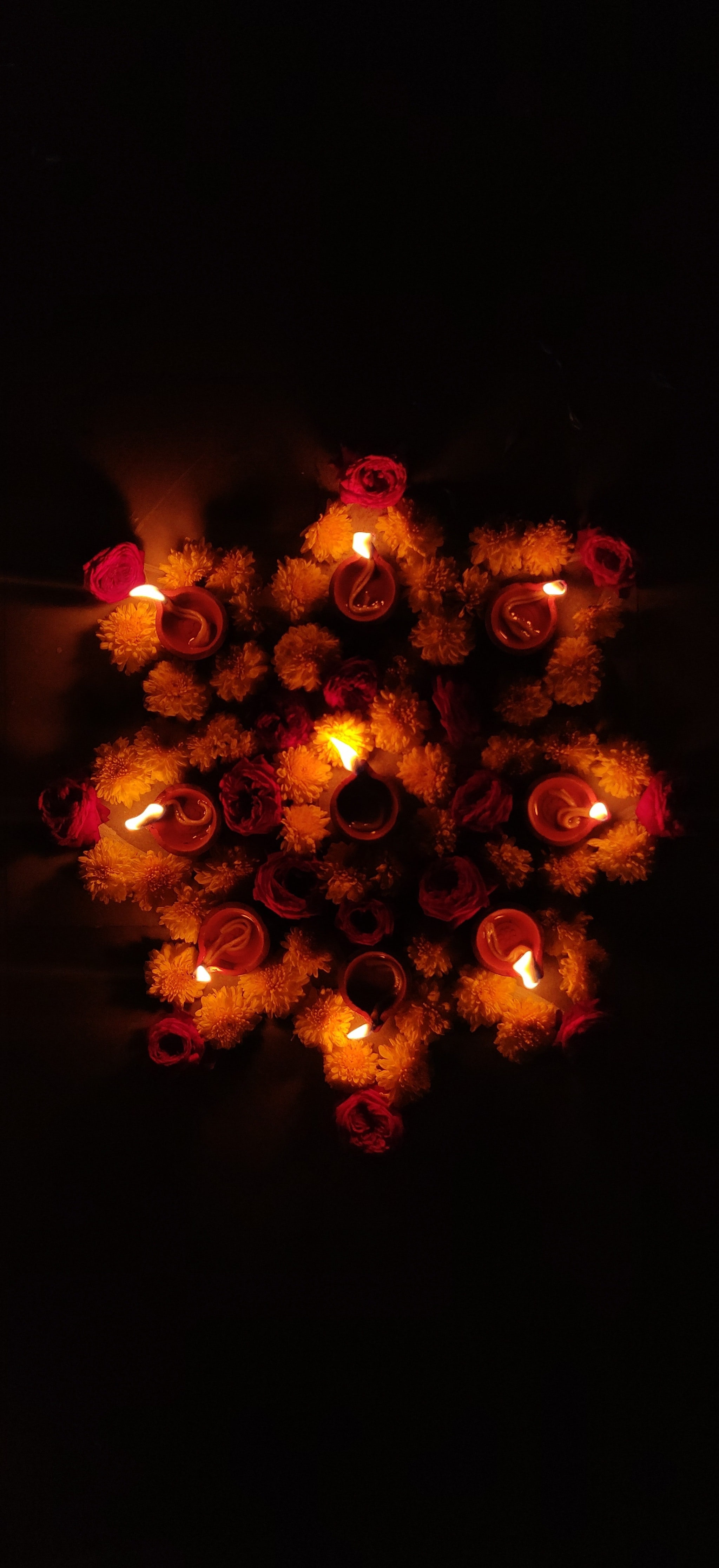 Low-light photograph of diyas arranged in a circle