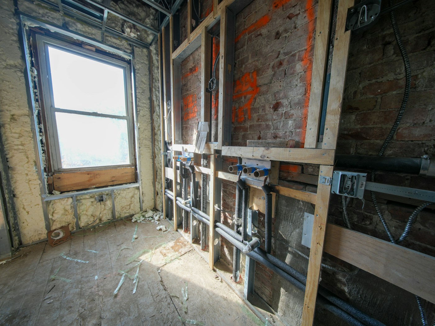 Interior under construction with exposed pipes and wiring