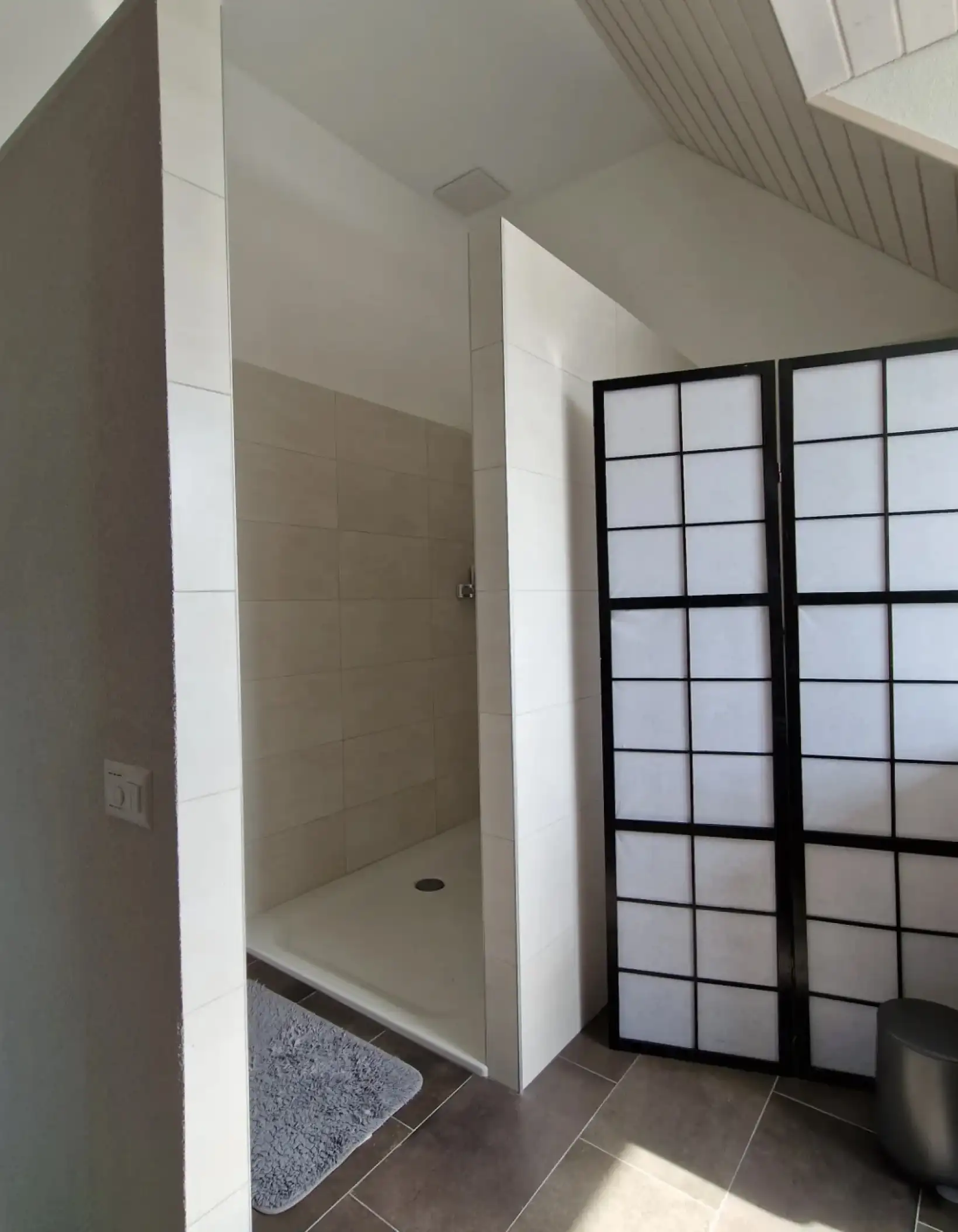 Salle de bain avec carrelage grès cérame beige et douche italienne.