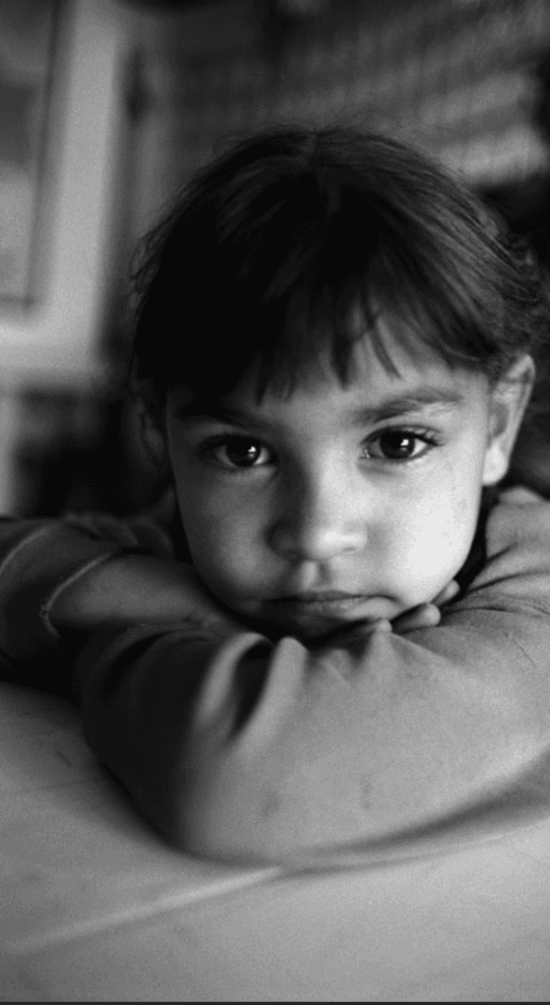 Black-and-white portrait of a young child resting her chin on her arms