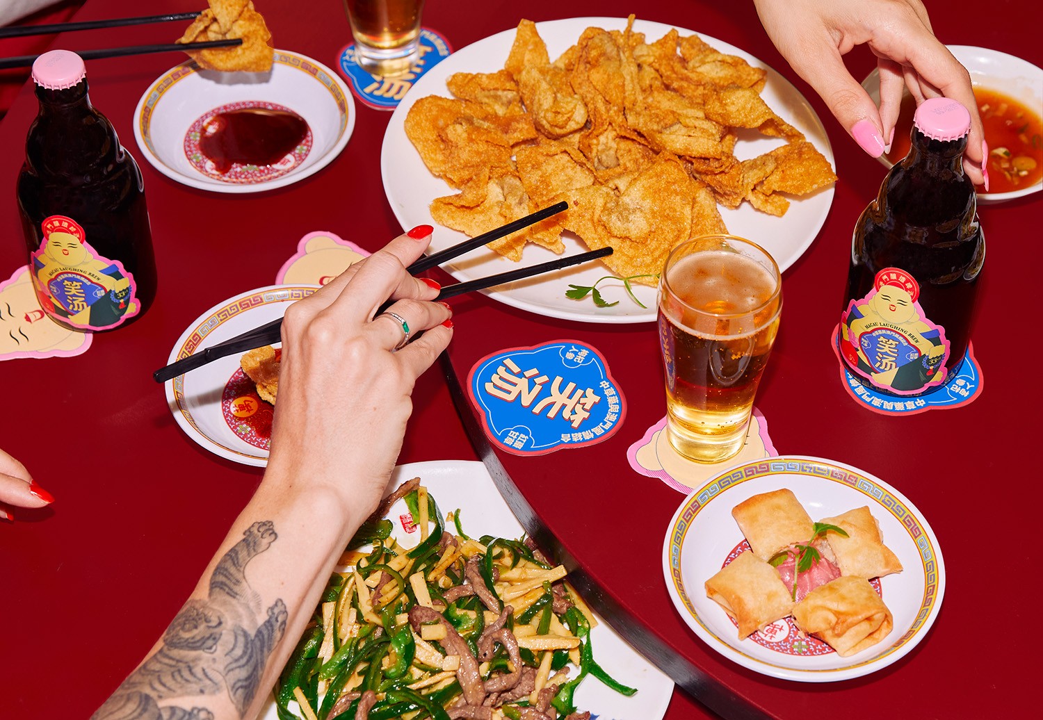 Macau Laughing Brew beer on a red table with Chinese dishes and people sharing a meal.