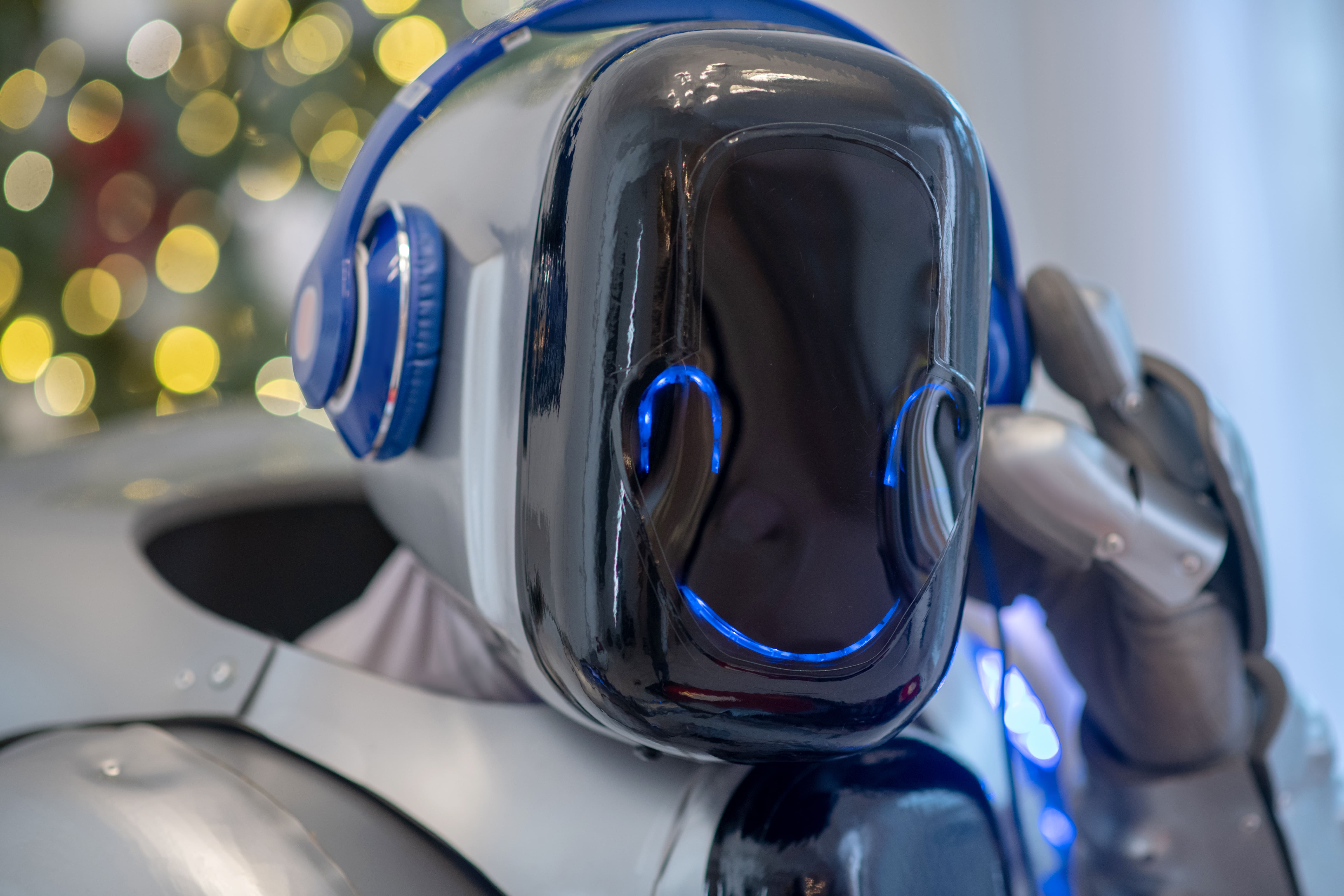 Close-up of humanoid robot wearing blue headphones with illuminated faceplate
