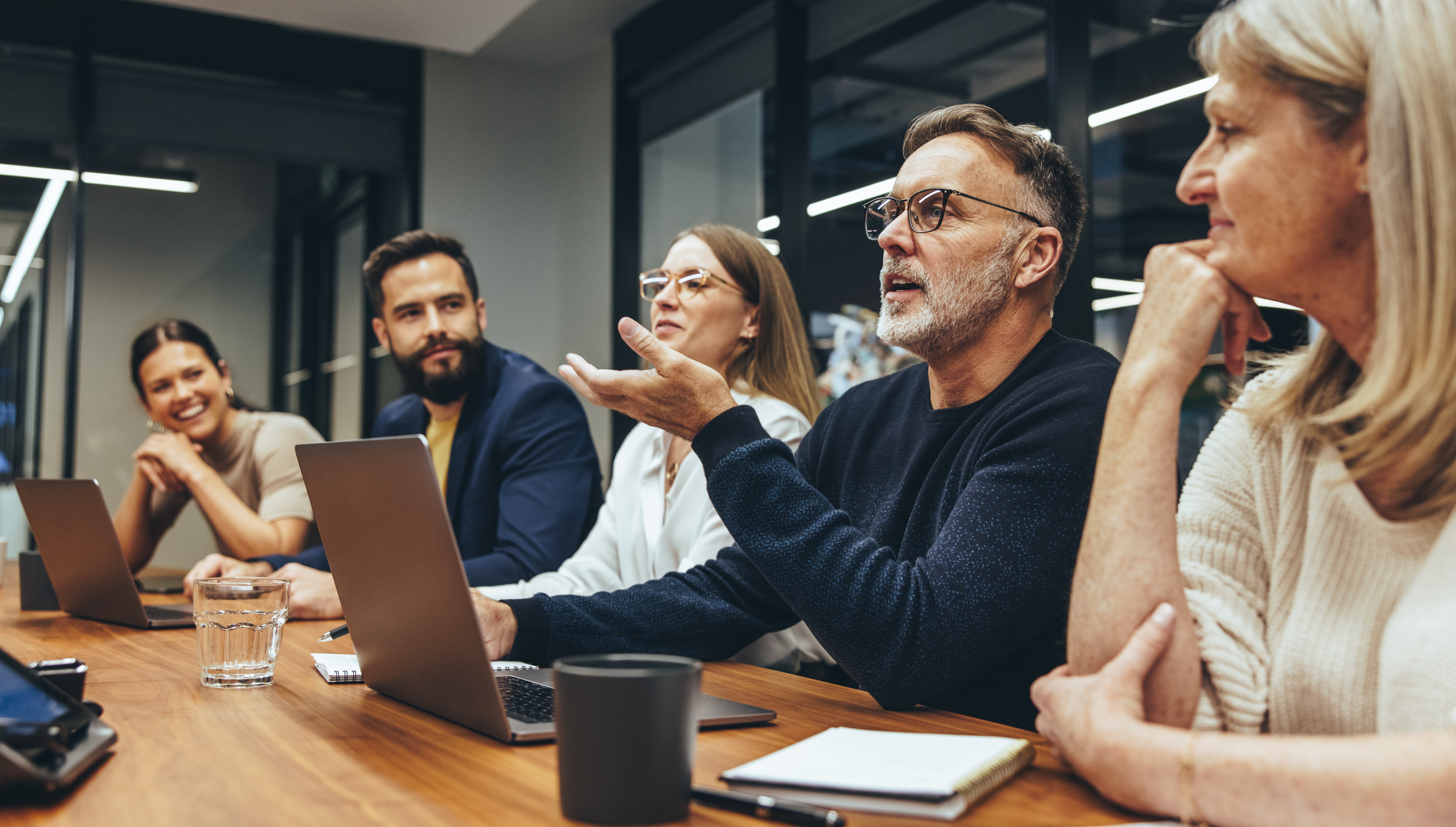 Executives and professionals in a bespoke corporate training workshop, discussing strategy, compliance, and management systems in a modern meeting room.