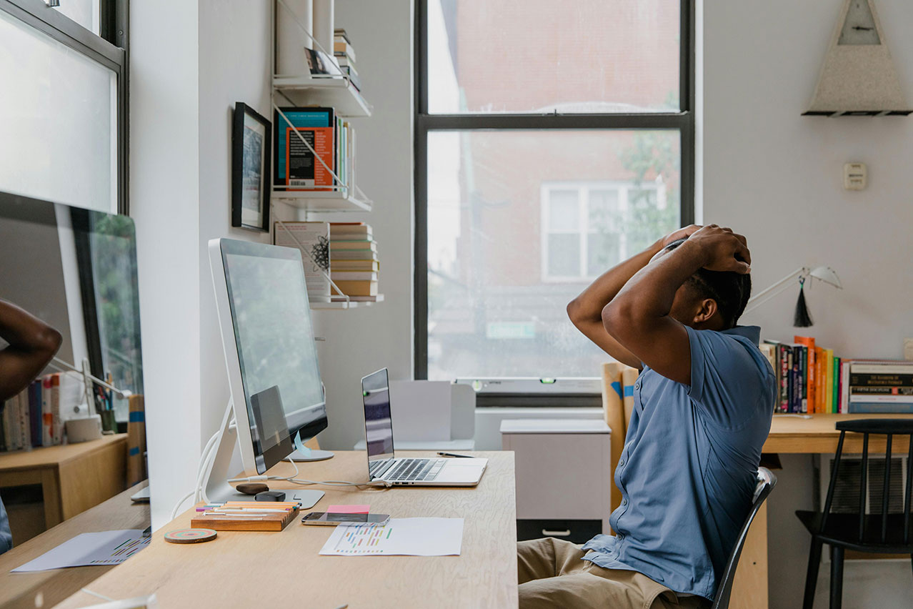 Don't let anxiety about fraud paralyze your business. Picture of man with hands on head in front of workspace