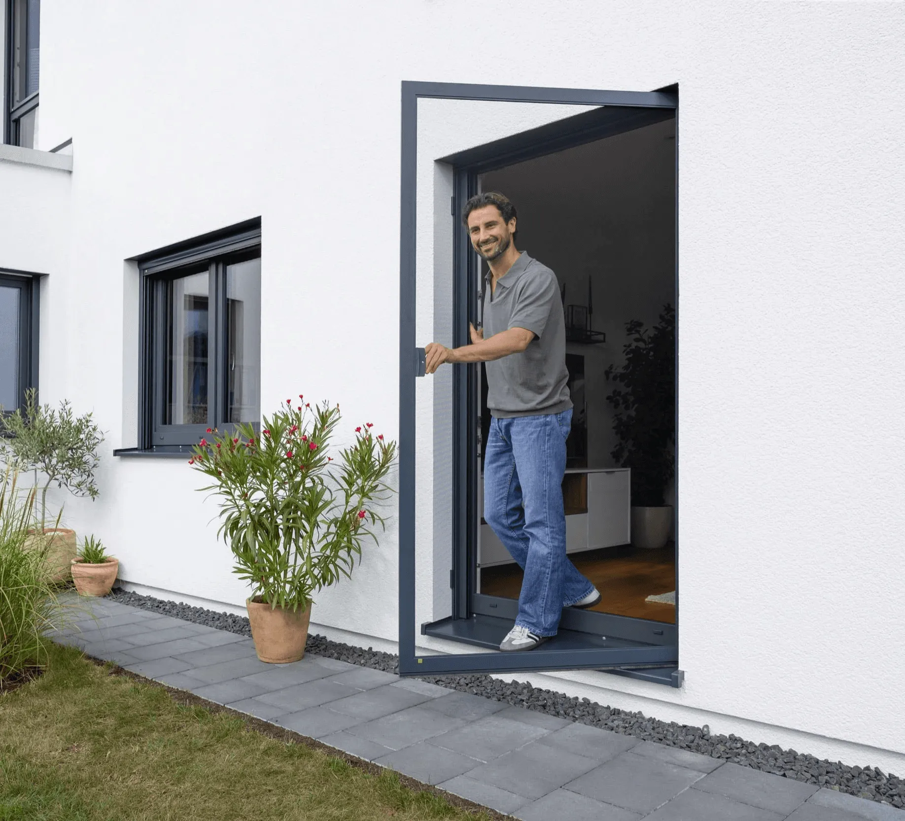 Mann öffnet eine Insektenschutztür auf der Terrasse