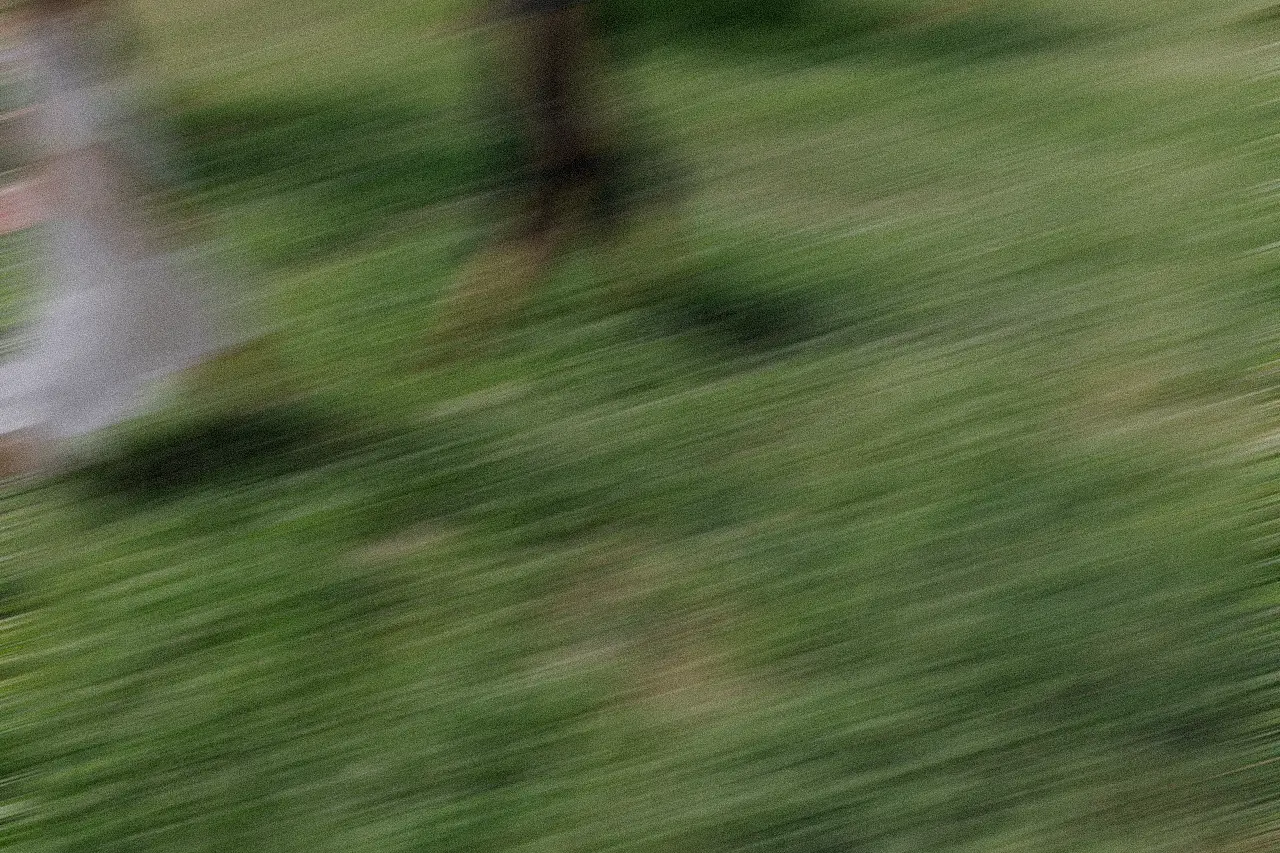 Motion-blurred landscape photo of rolling hills under a cloudy blue sky, with warm earthy tones in the terrain conveying a sense of movement.