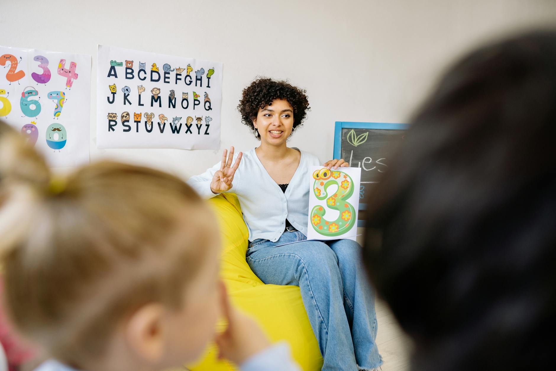 Close-up of a classroom wall covered in alphabet posters, labeled drawings, and bright vocabulary charts.