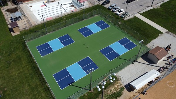 Aerial view of multi-court pickleball facility with blue court surfaces, built on a court footprint that could also support TYPTI