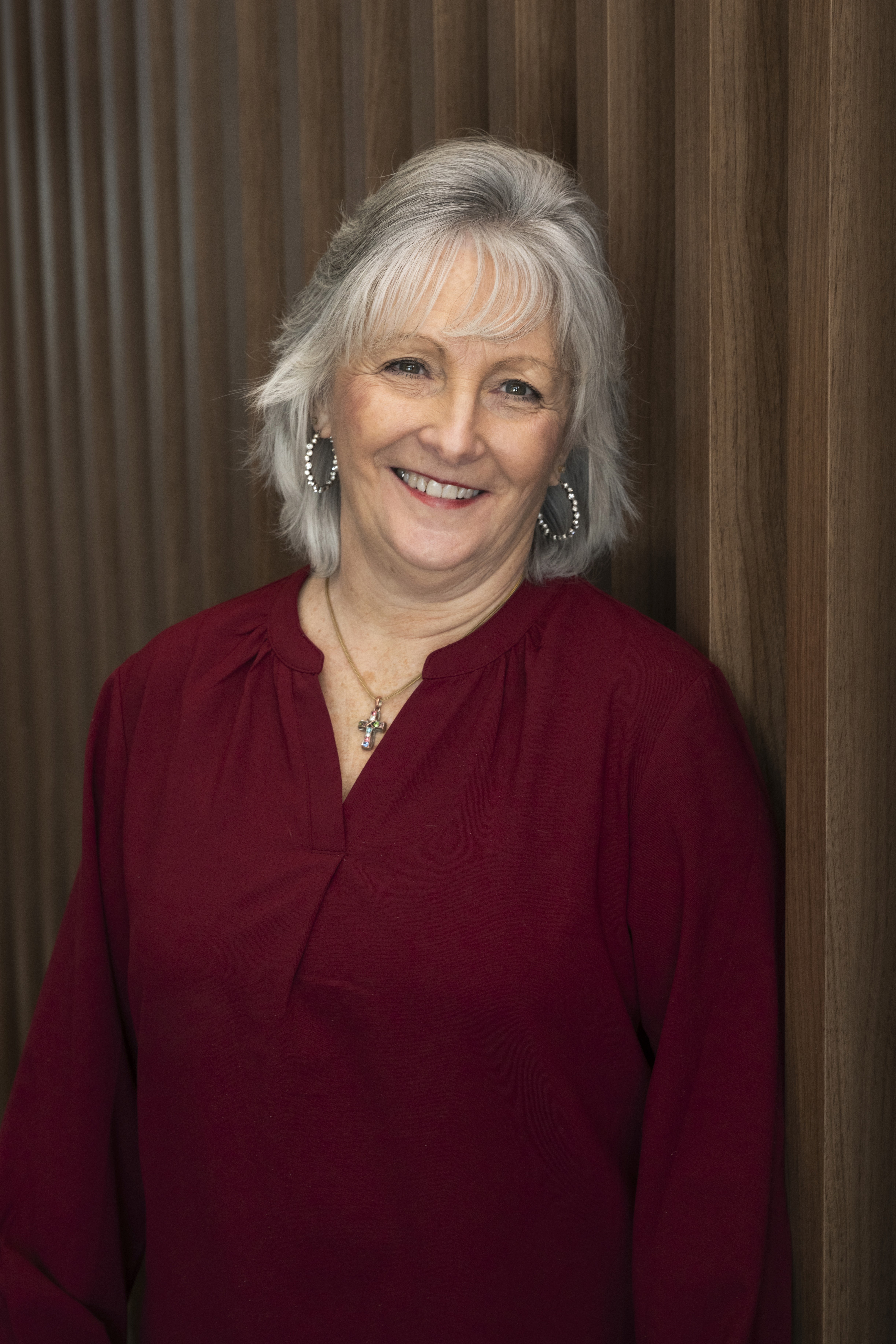 Portrait of a woman in a beige blazer with red lipstick, neutral background.