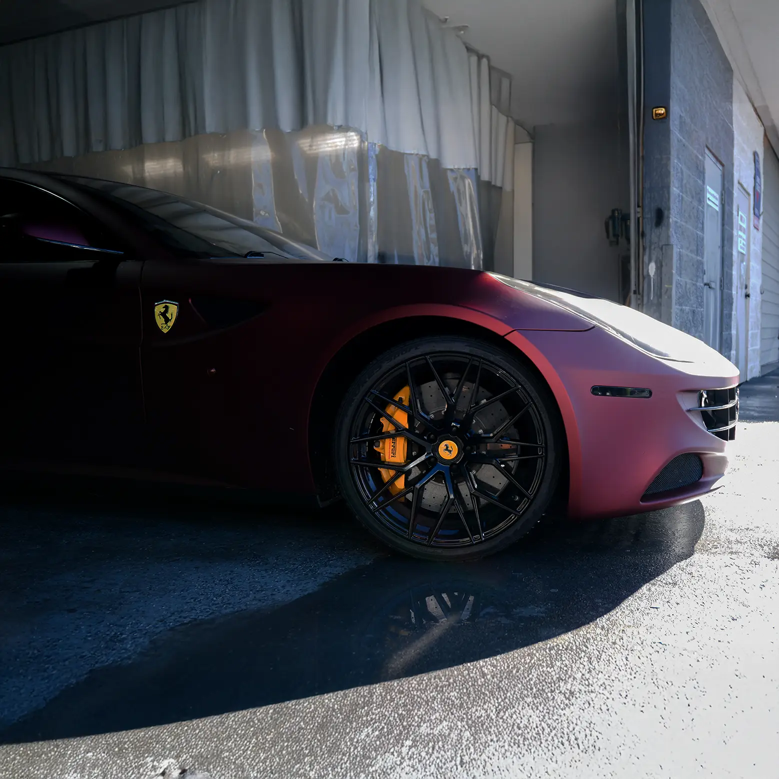Ferrari parked inside a professional auto body shop after repair service.