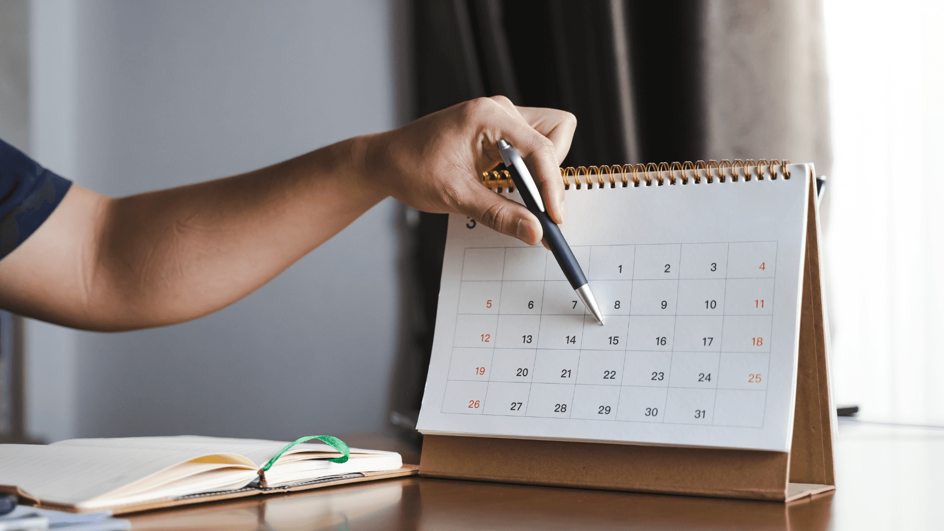 Woman pointing to a date on a desk calendar while tracking her menstrual cycle