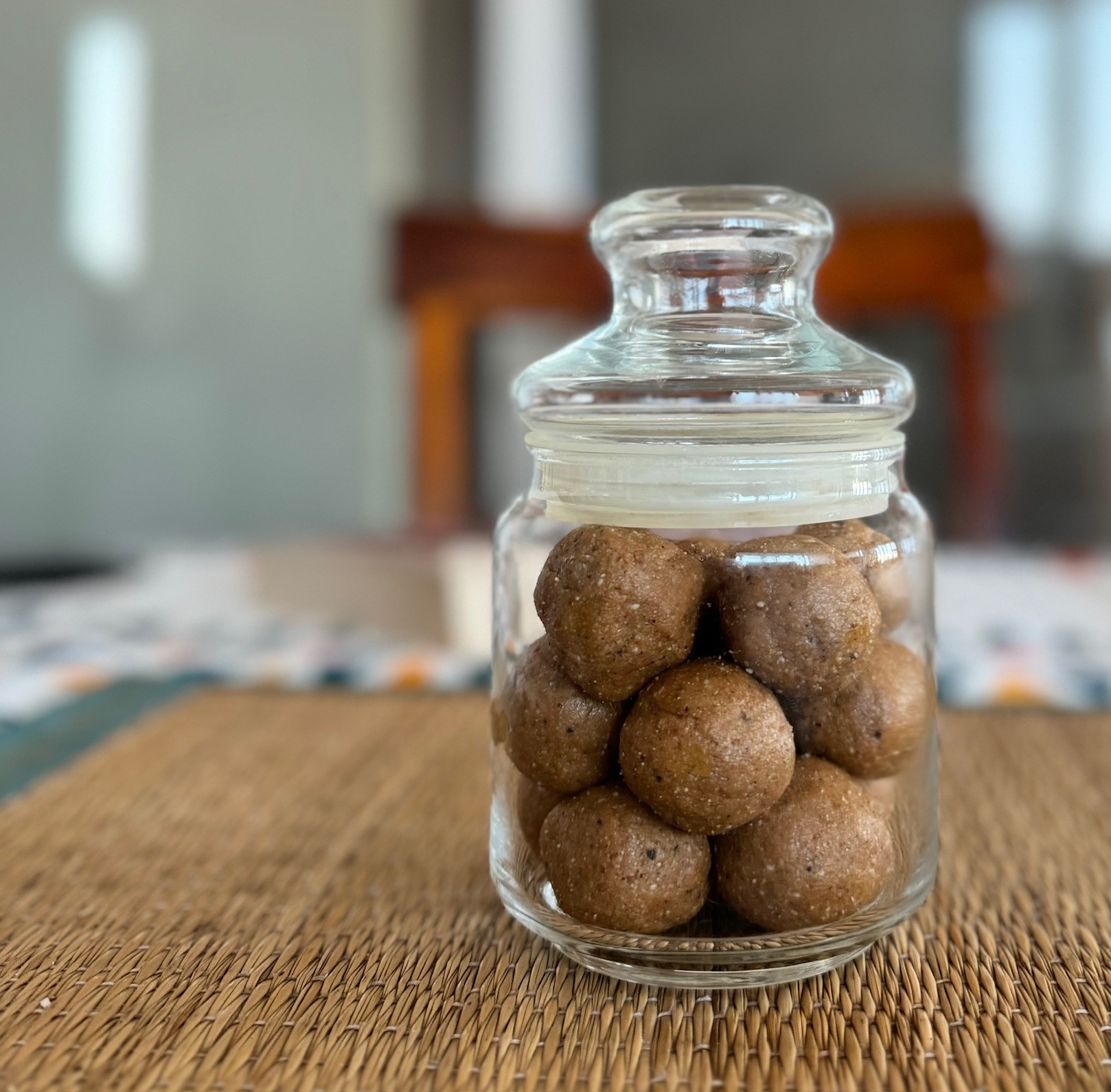 A bottle of til gul ladoos set on a dining table.