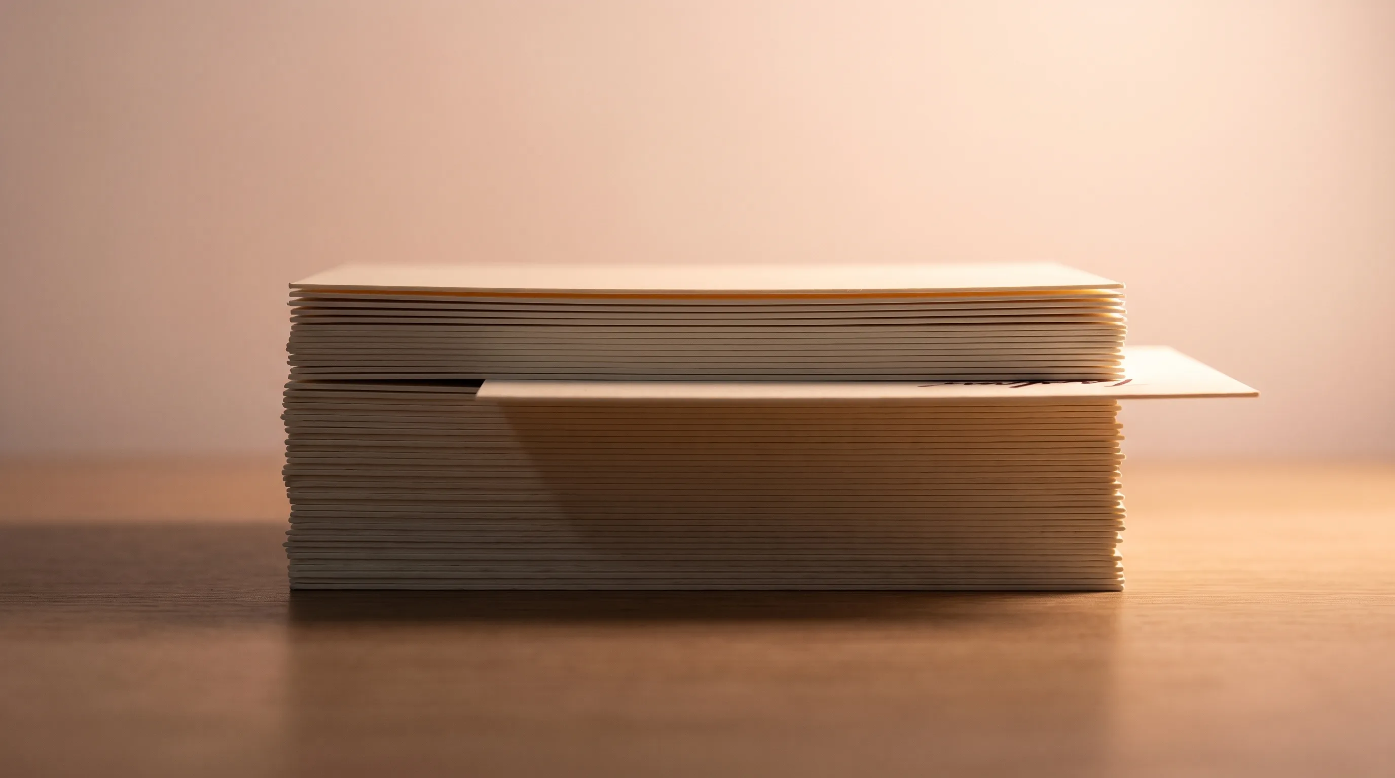 A stack of index cards seen edge on, with one card pulled slightly proud of the others and catching the light