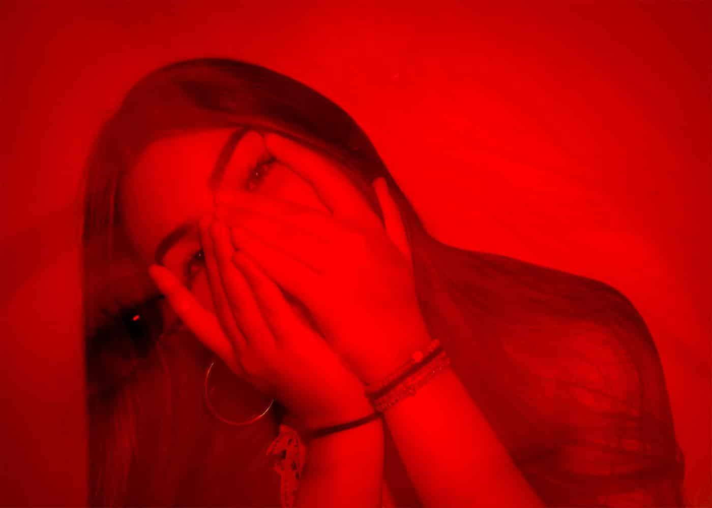 Do red light therapy masks work - Woman covering her mouth with a red filter on